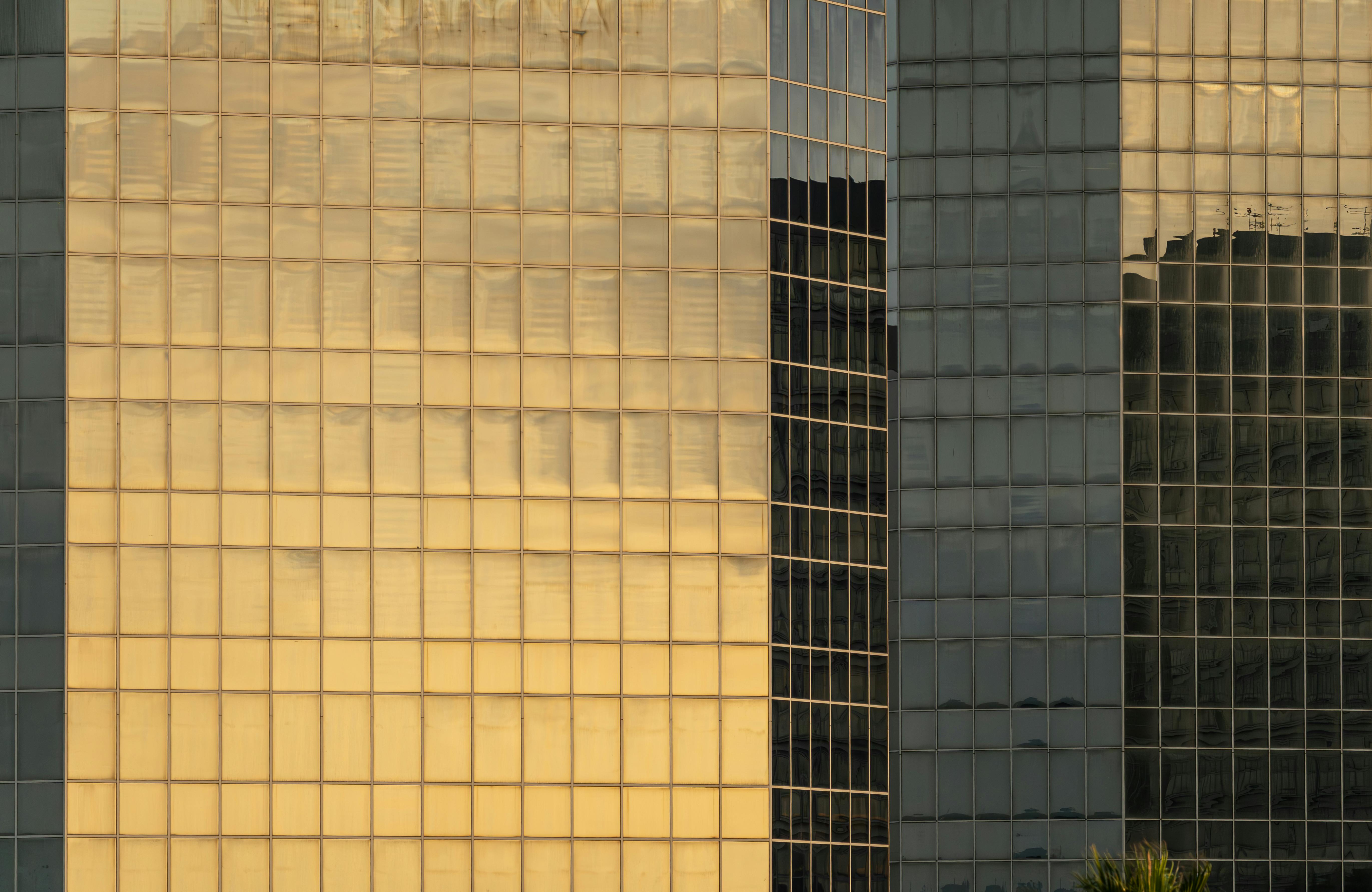 Gratis Fantastiske refleksjoner av solnedgangsfarger på en moderne glassbygningsfasade skaper et varmt, abstrakt mønster. Arkivbilde