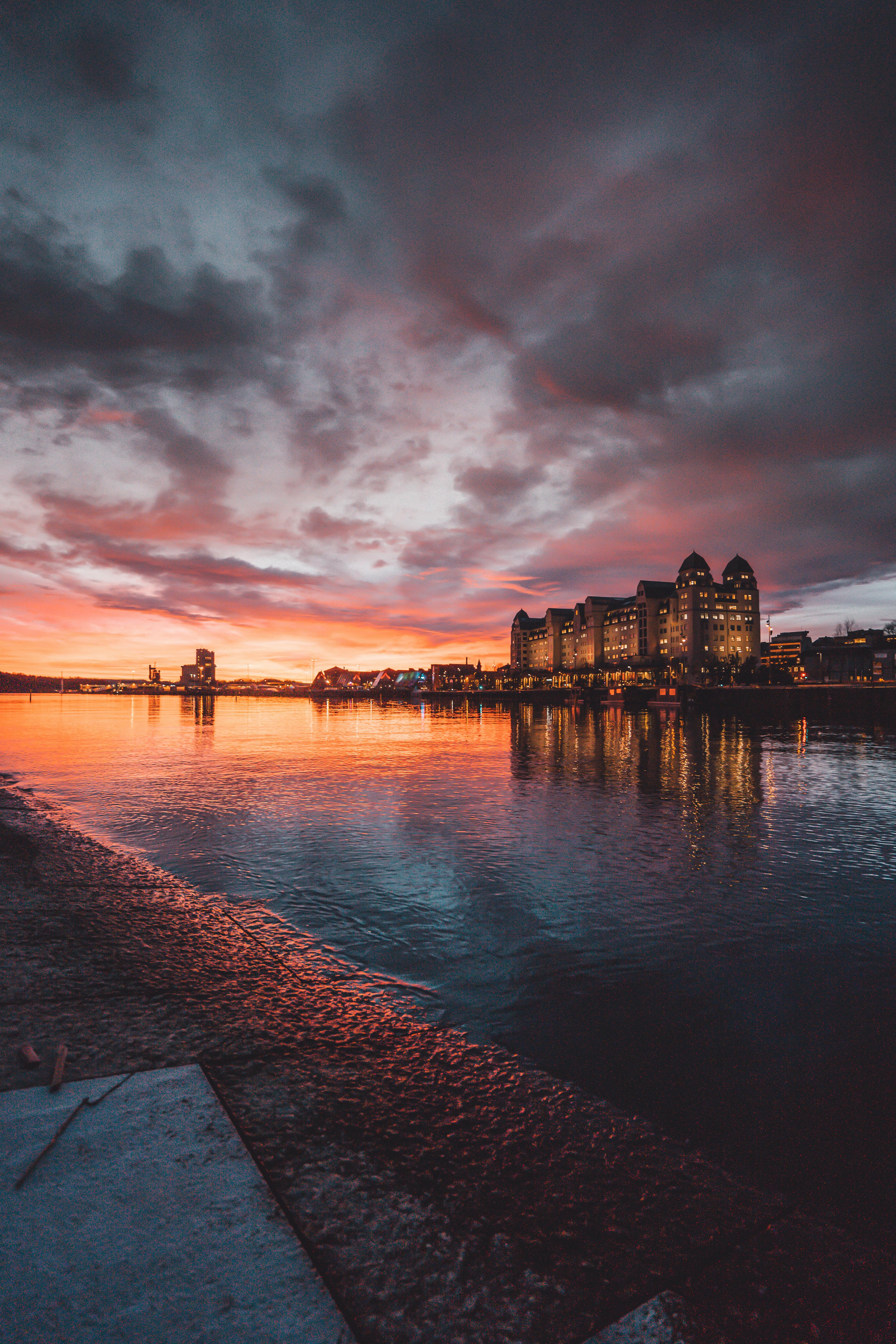 日落时分，奥斯陆色彩缤纷的天际线倒映在平静的水面上，展现出引人注目的云层与城市灯光