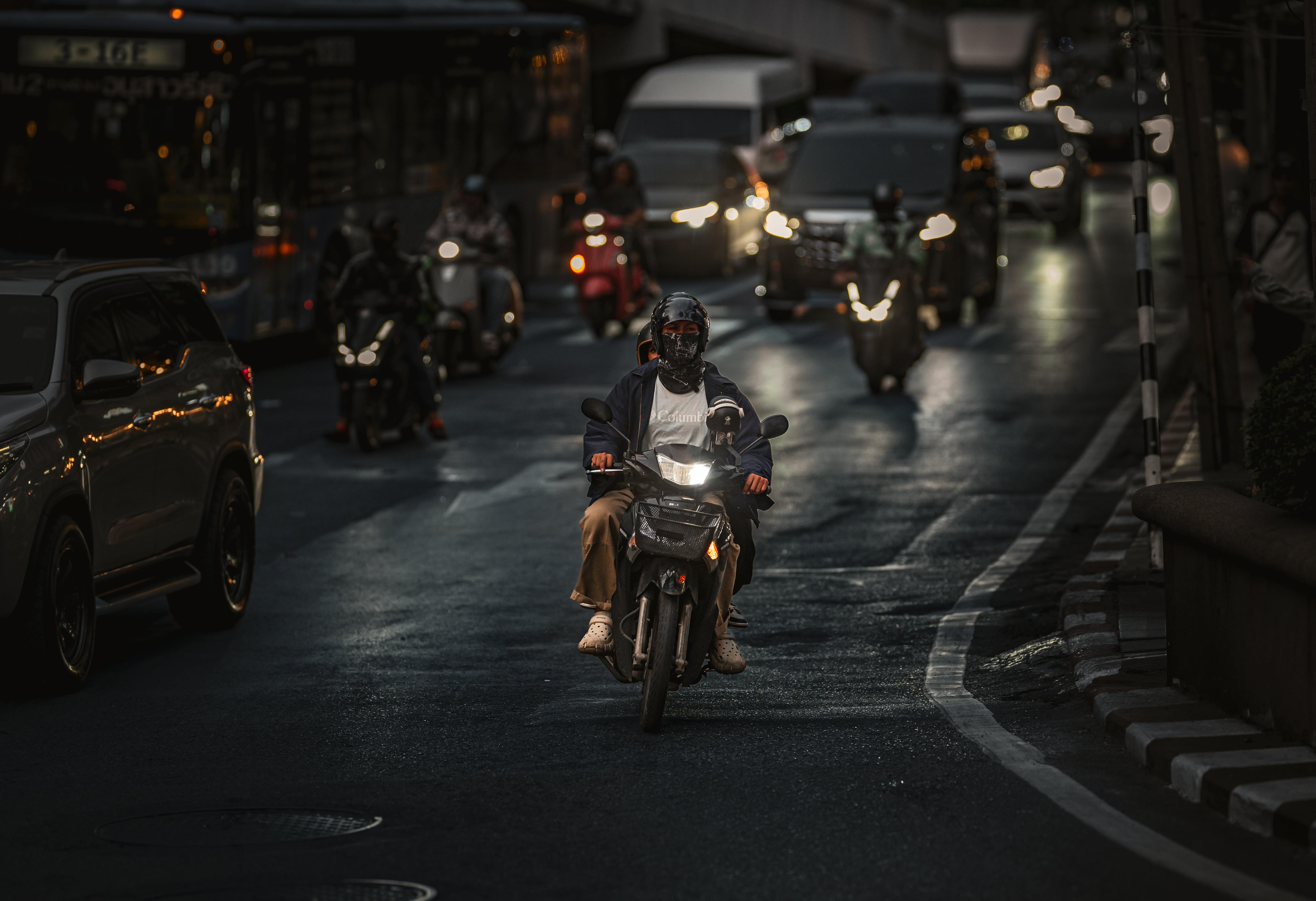 Безкоштовне Мотоцикліст їде крізь жвавий вечірній рух у Бангкоку, Таїланд. стокове фото