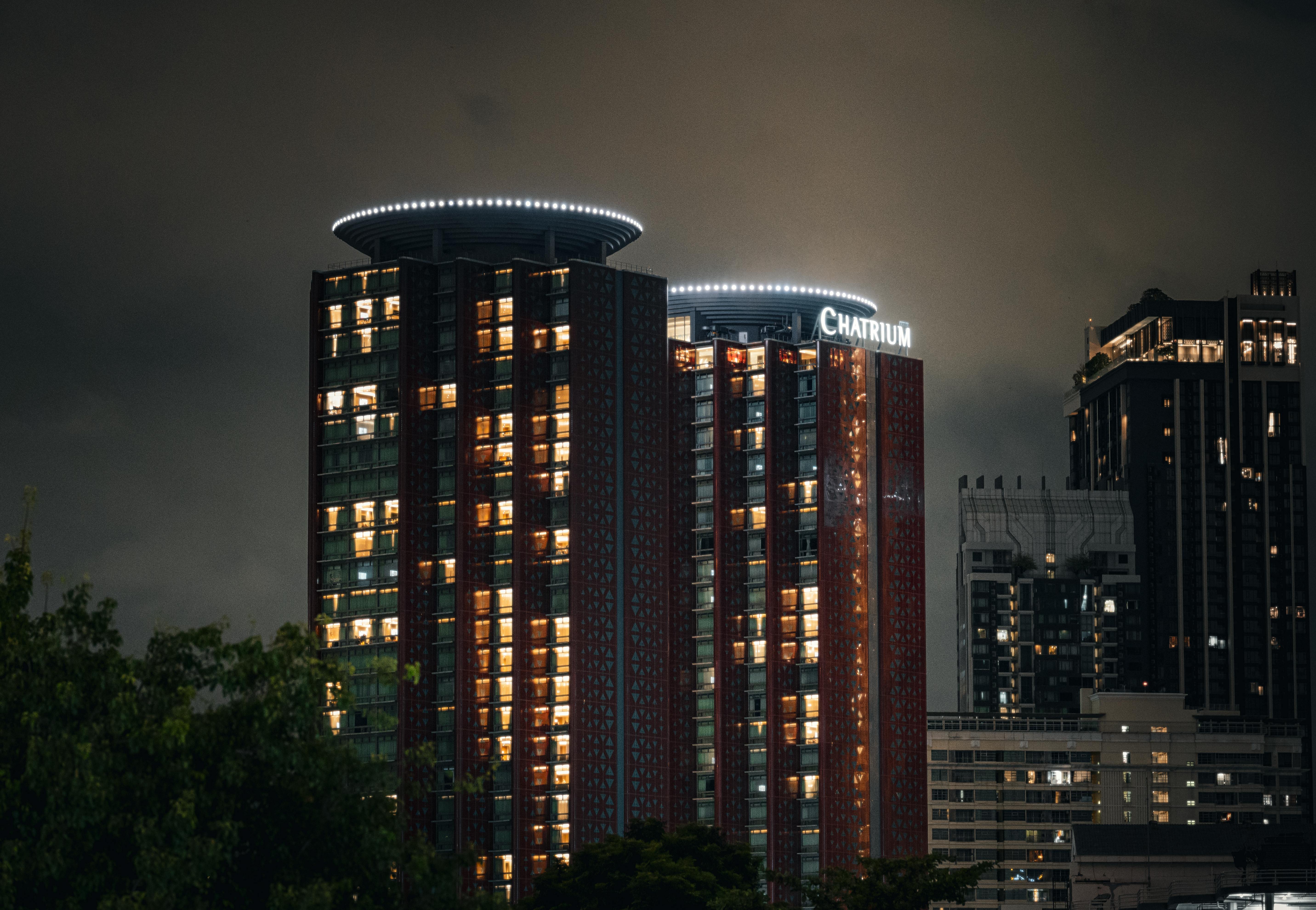 Gratis Det oplyste Chatrium Hotel i Bangkoks skyline om natten, der fremviser moderne arkitektur. Lagerfoto