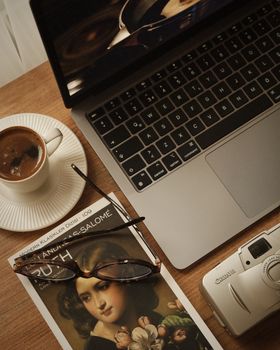 A relaxing setup with coffee, a book, and a laptop on a wooden table.