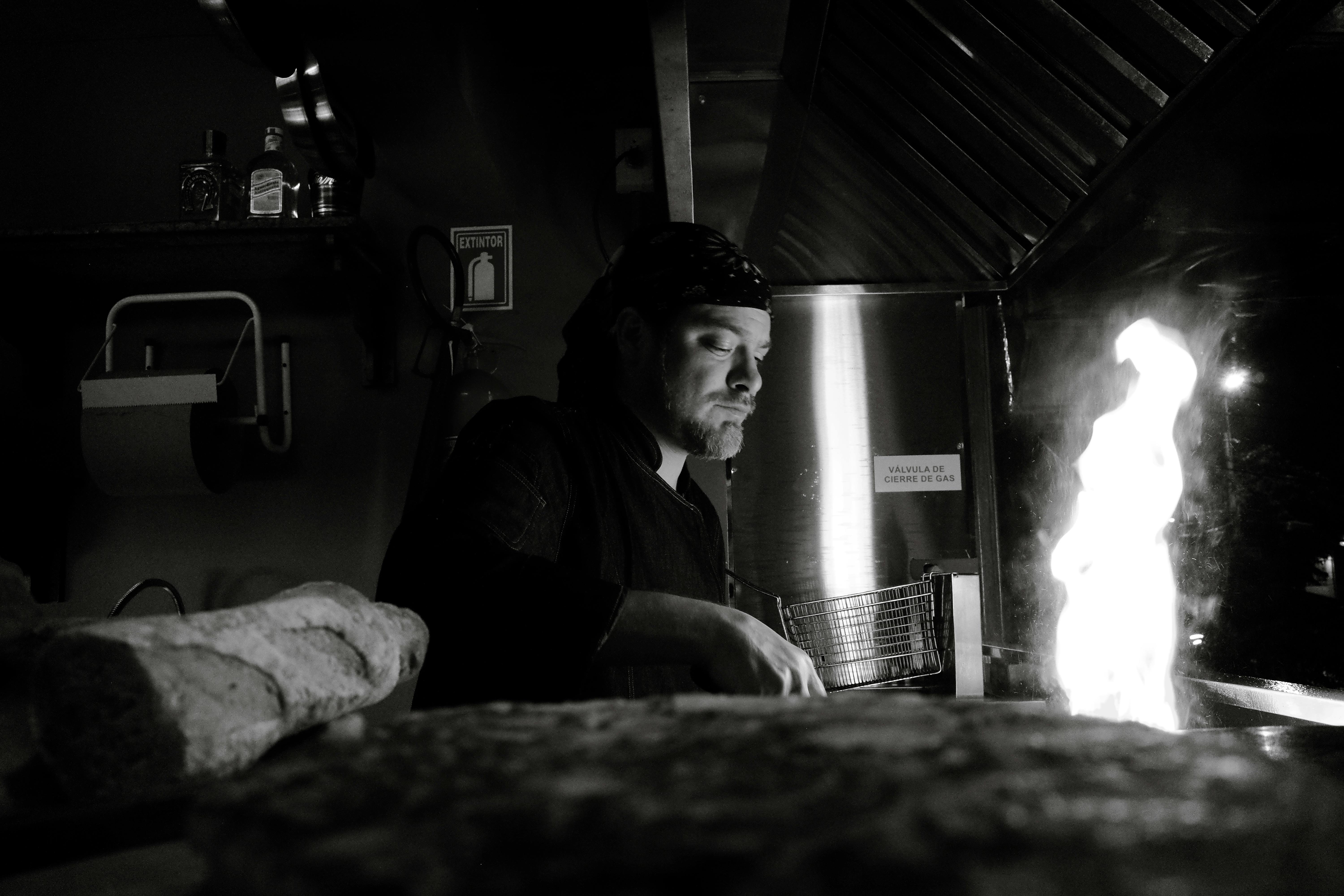 A chef skillfully prepares food over an open flame in a commercial kitchen.