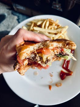 A delicious cheeseburger with toppings and a side of golden fries on a white plate.
