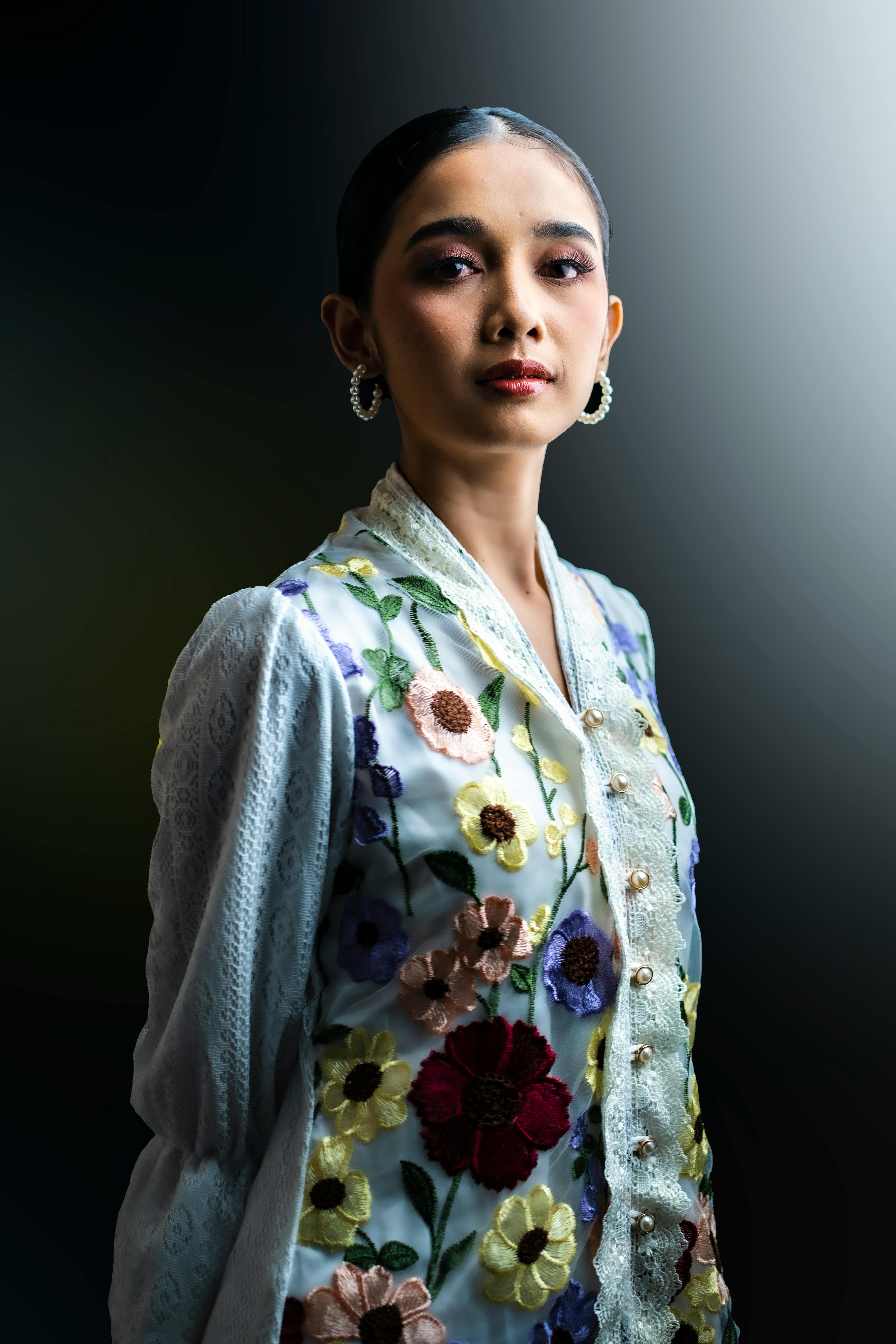 Miễn phí Chân dung một người phụ nữ mặc váy thêu hoa với đôi bông tai thanh lịch, nổi bật trên nền tối. Ảnh lưu trữ