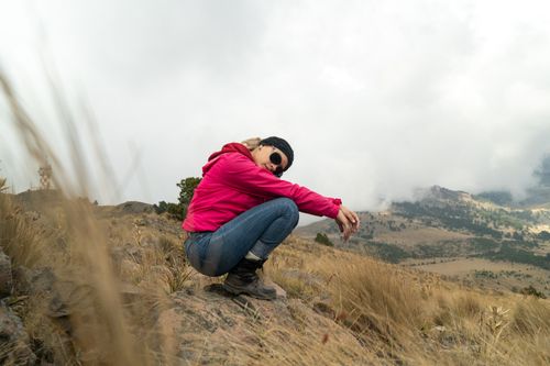 Free Woman in pink jacket enjoys a mountain hike, surrounded by nature's beauty. Stock Photo