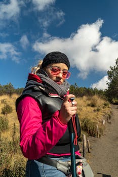 Woman in winter attire hiking under clear blue skies.