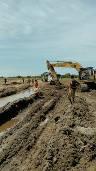 A group of workers with excavators at a rural construction site, illustrating outdoor manual labor.