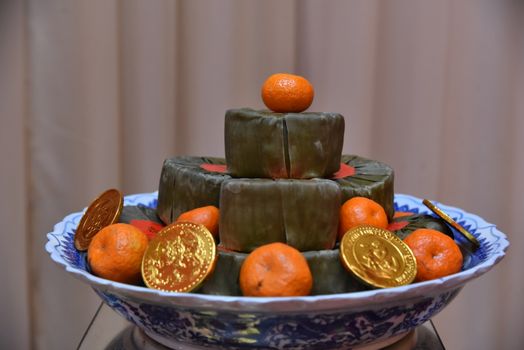 A decorative plate with Nian Gao, oranges, and gold coins, symbolizing prosperity.