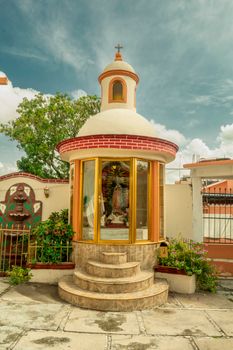 Beautiful outdoor religious shrine with a dome and glass encasement under a vibrant blue sky.