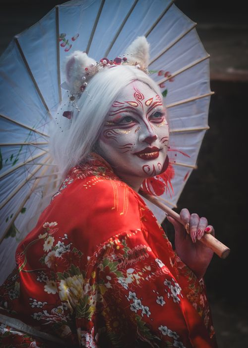 Free Vibrant portrait of a person in geisha makeup and kimono holding a parasol. Stock Photo
