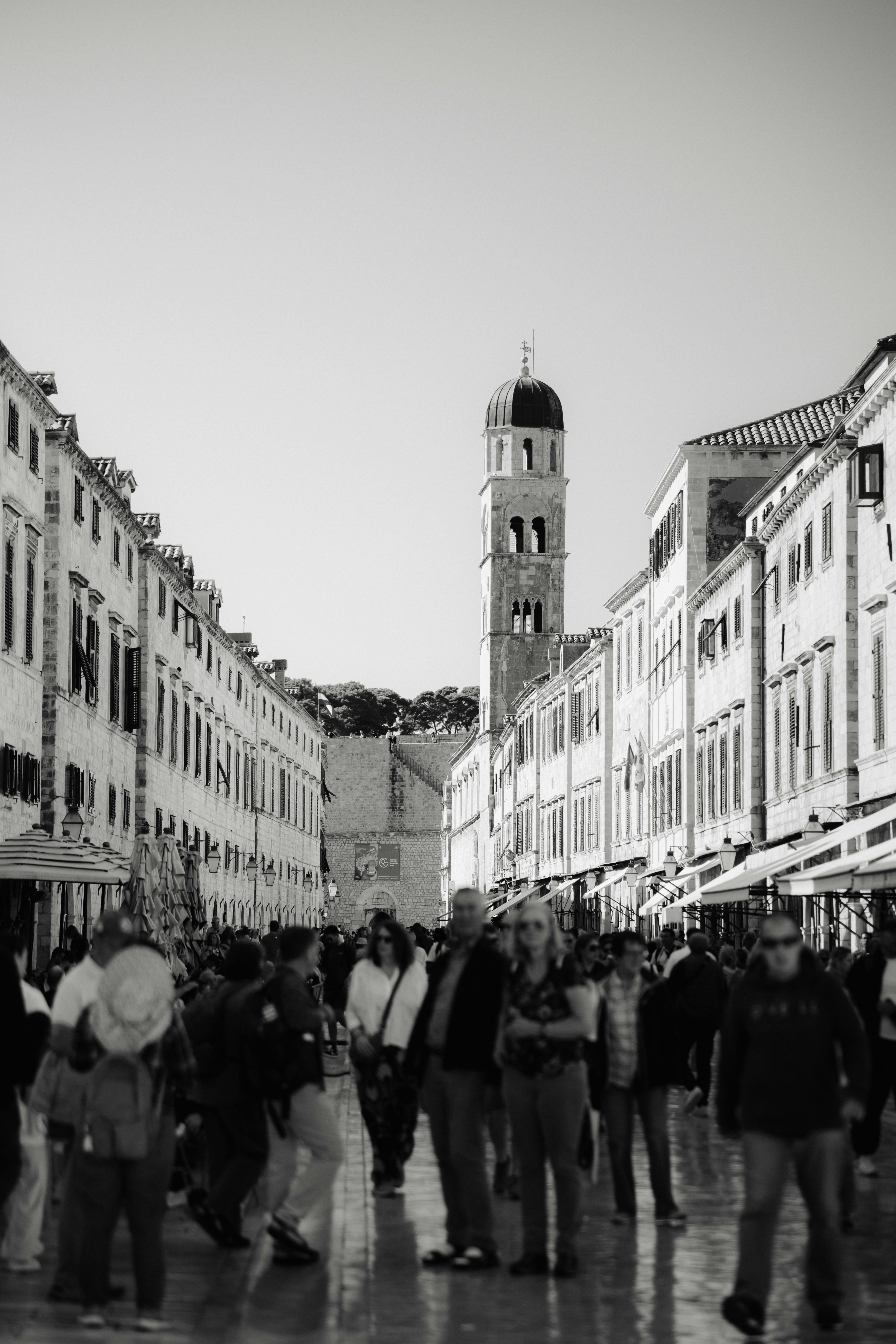 Gratis Svart-hvitt-bilde av en travel gate i Dubrovnik med det ikoniske klokketårnet. Arkivbilde