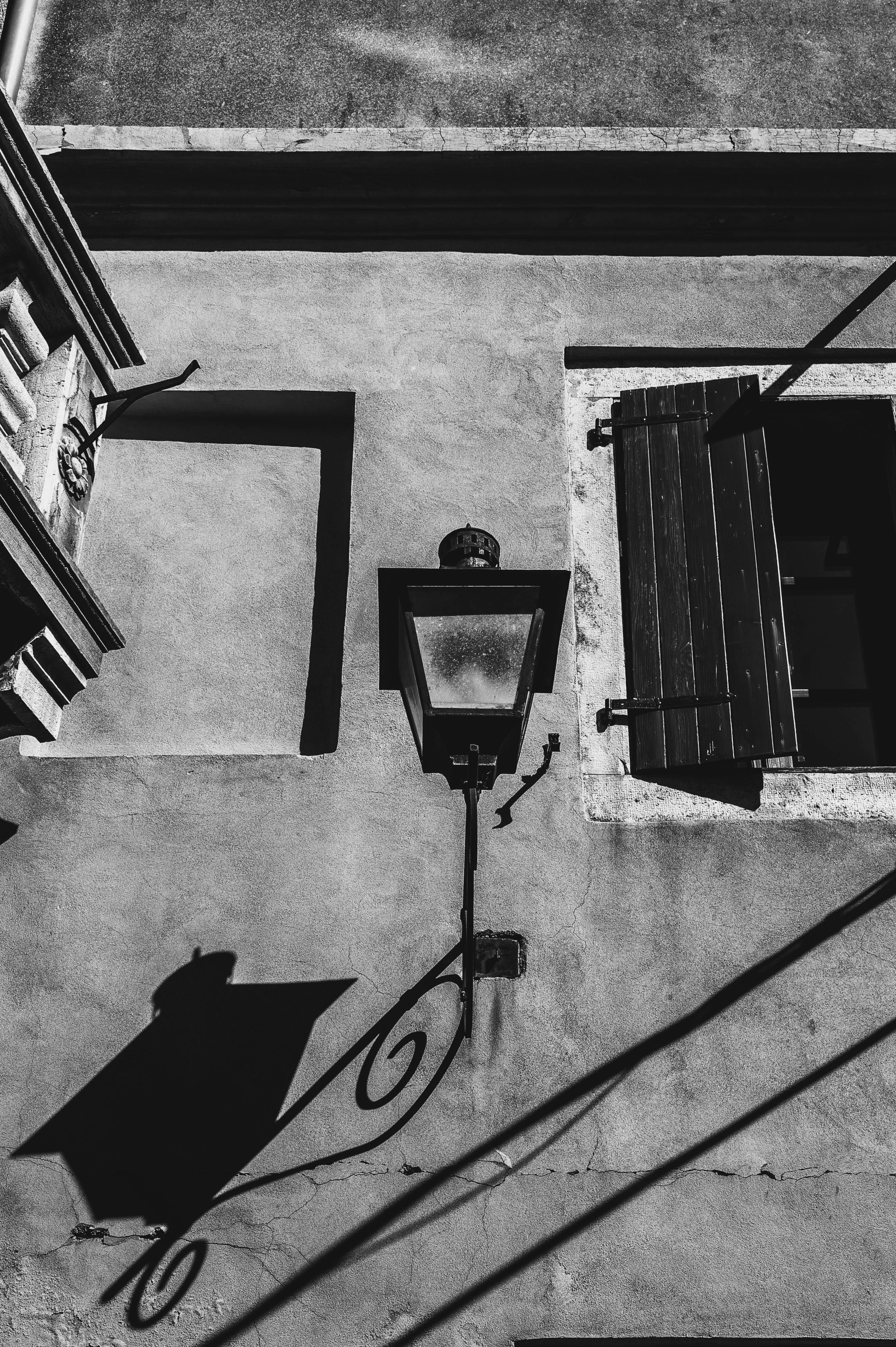 Zadarmo Čiernobiela fotografia mestskej steny s lampou a tieňom okna vo vintage štýle. Fotka z fotobanky