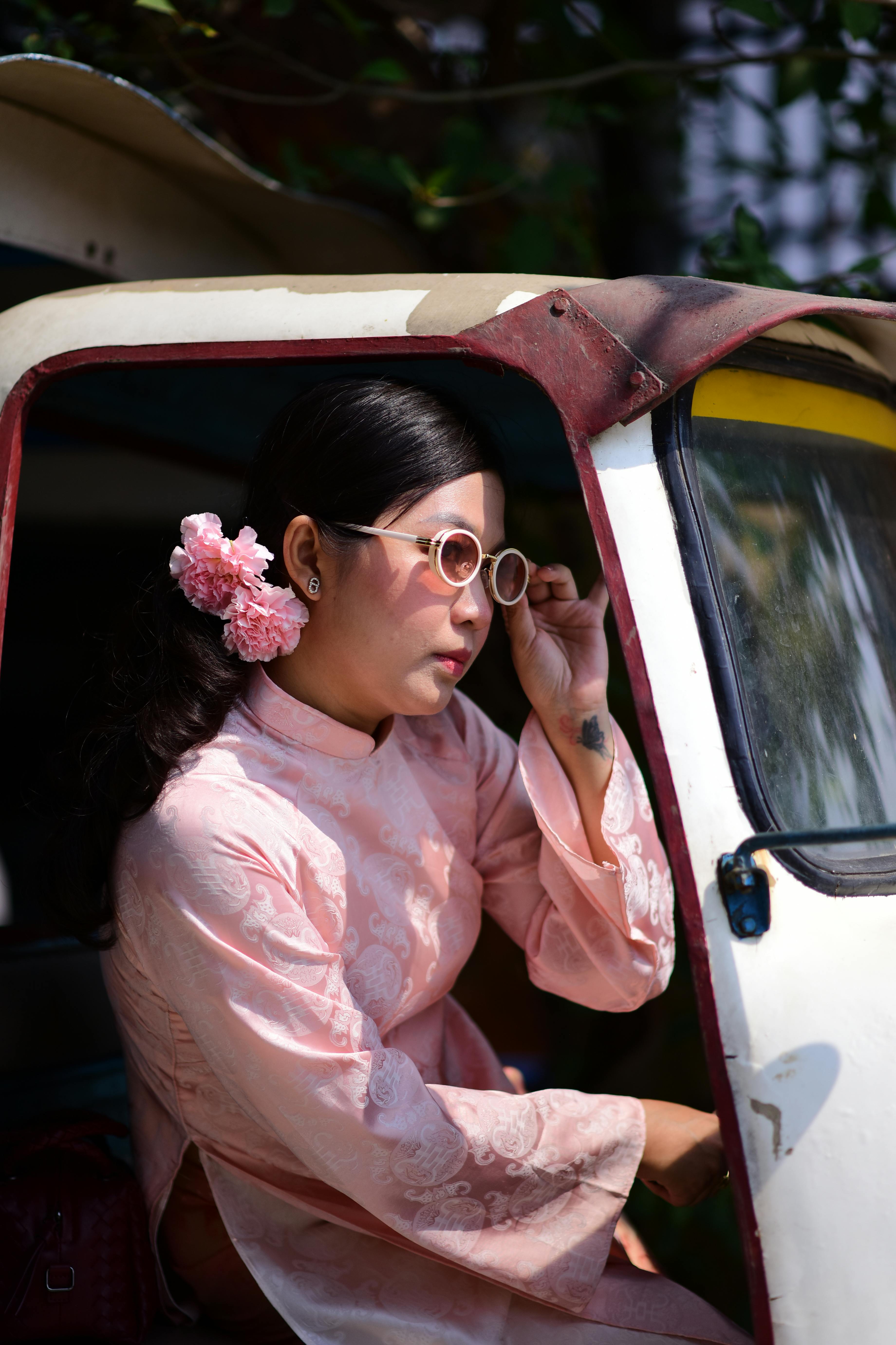 ingyenes Egy hagyományos öltözéket és napszemüveget viselő nő kinéz egy járműből, megtestesítve a kulturális stílust. Stockfotó