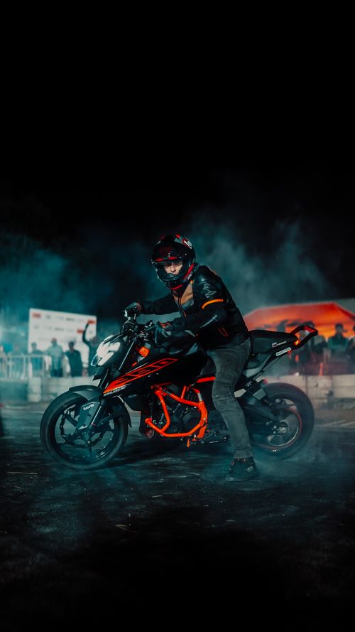 Free Rider performing a daring motorcycle stunt at night amidst dramatic smoke and lights. Stock Photo