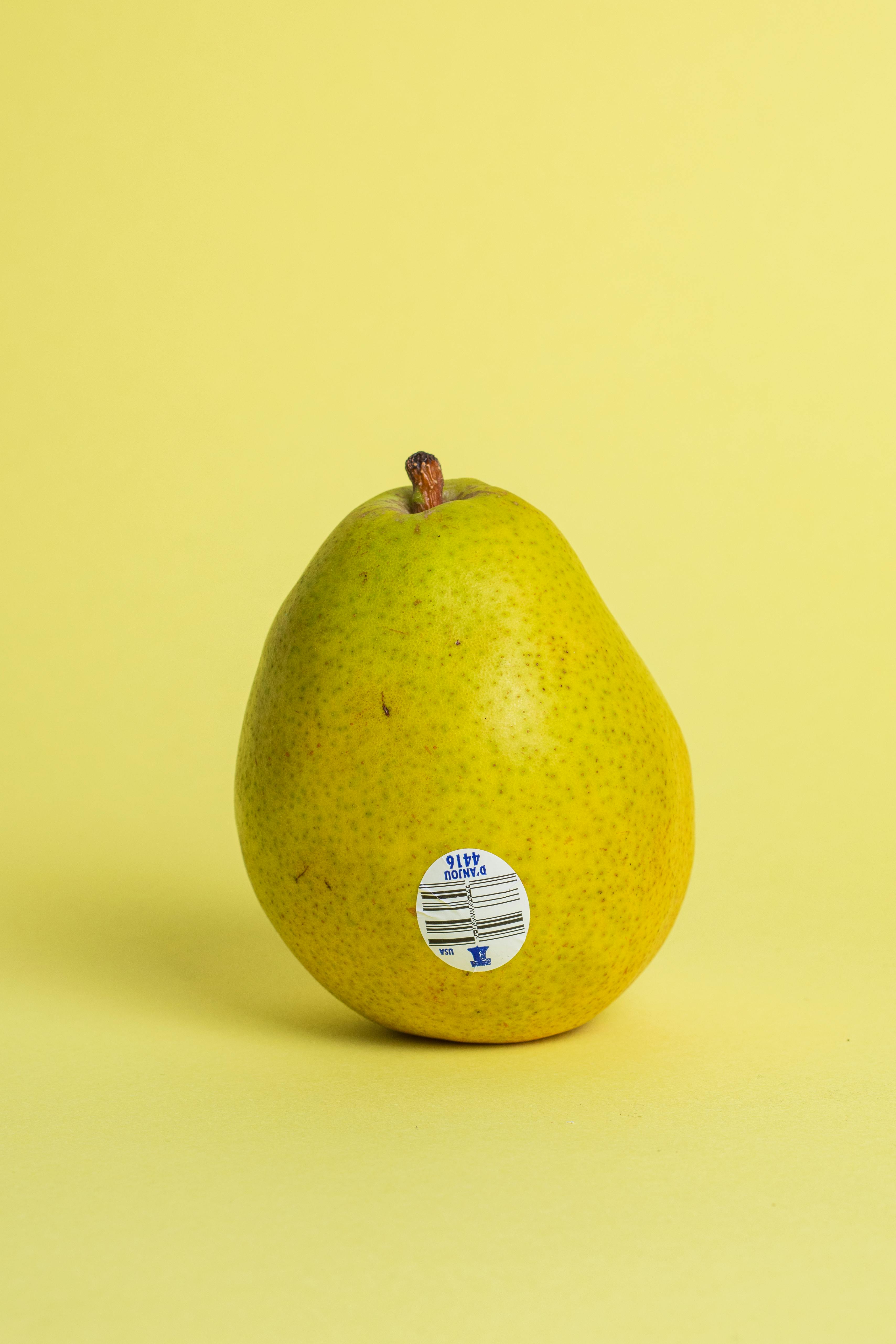 Gratis Una vivace natura morta raffigurante una singola pera su uno sfondo giallo. Foto a disposizione