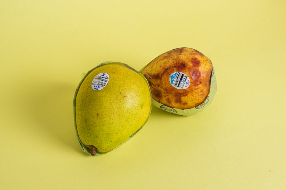 Two pears on a yellow surface, captured in a minimalist still life setup.