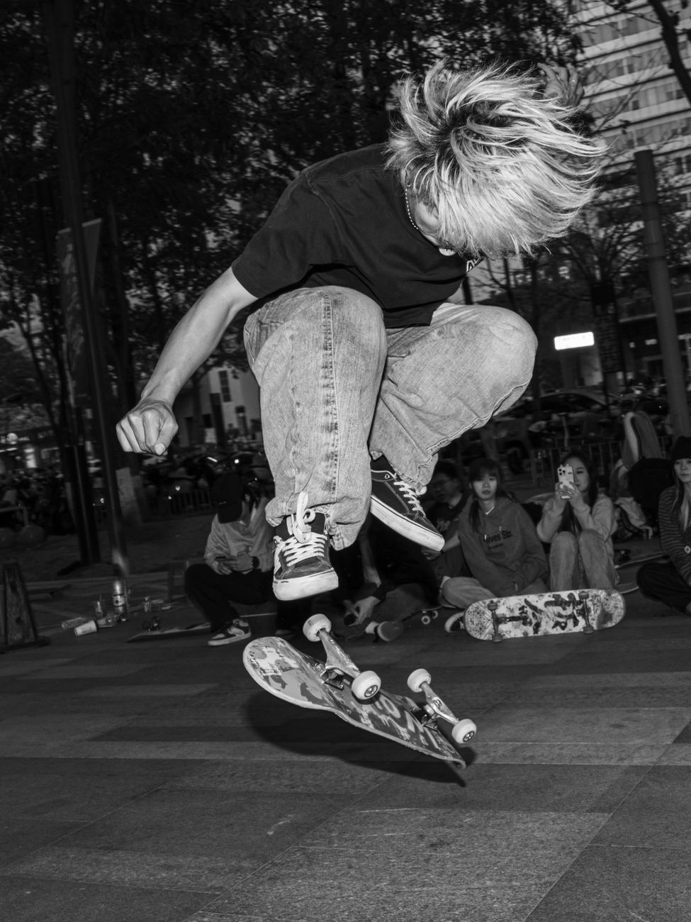 Skateboarder performs a mid-air trick in a vibrant city setting at night.. skateboarder, performs, trick