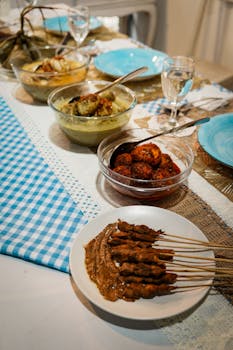 A vibrant spread of Indonesian dishes including satay and spicy curry on a festive dining table.