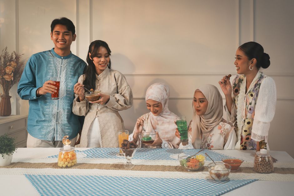 Group of friends dressed traditionally sharing a meal indoors during a festive celebration.