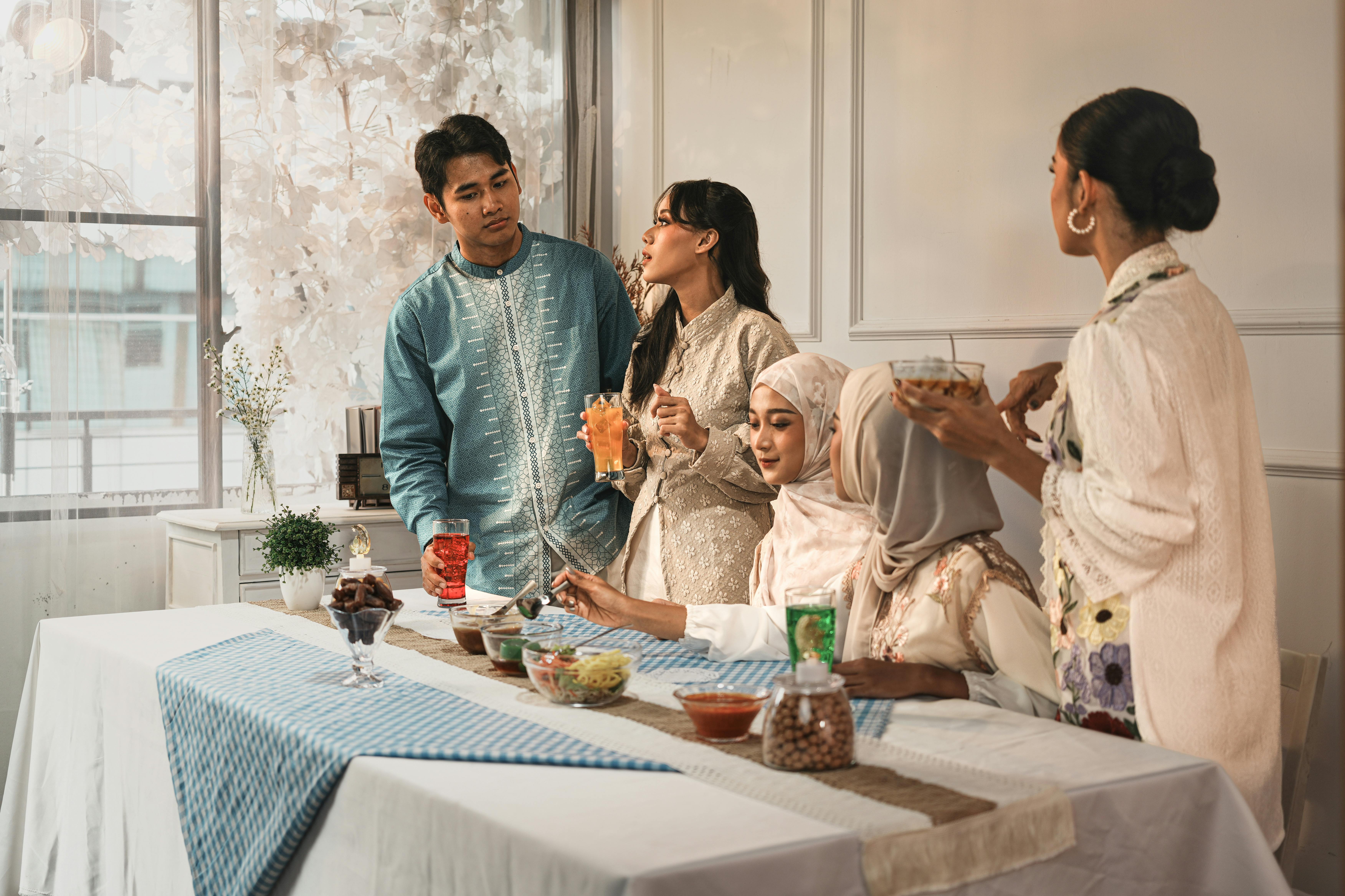 ingyenes Egy sokszínű csoport elegáns, hagyományos ruhába öltözve, italokat és harapnivalókat fogyasztva vacsorázik bent. Stockfotó