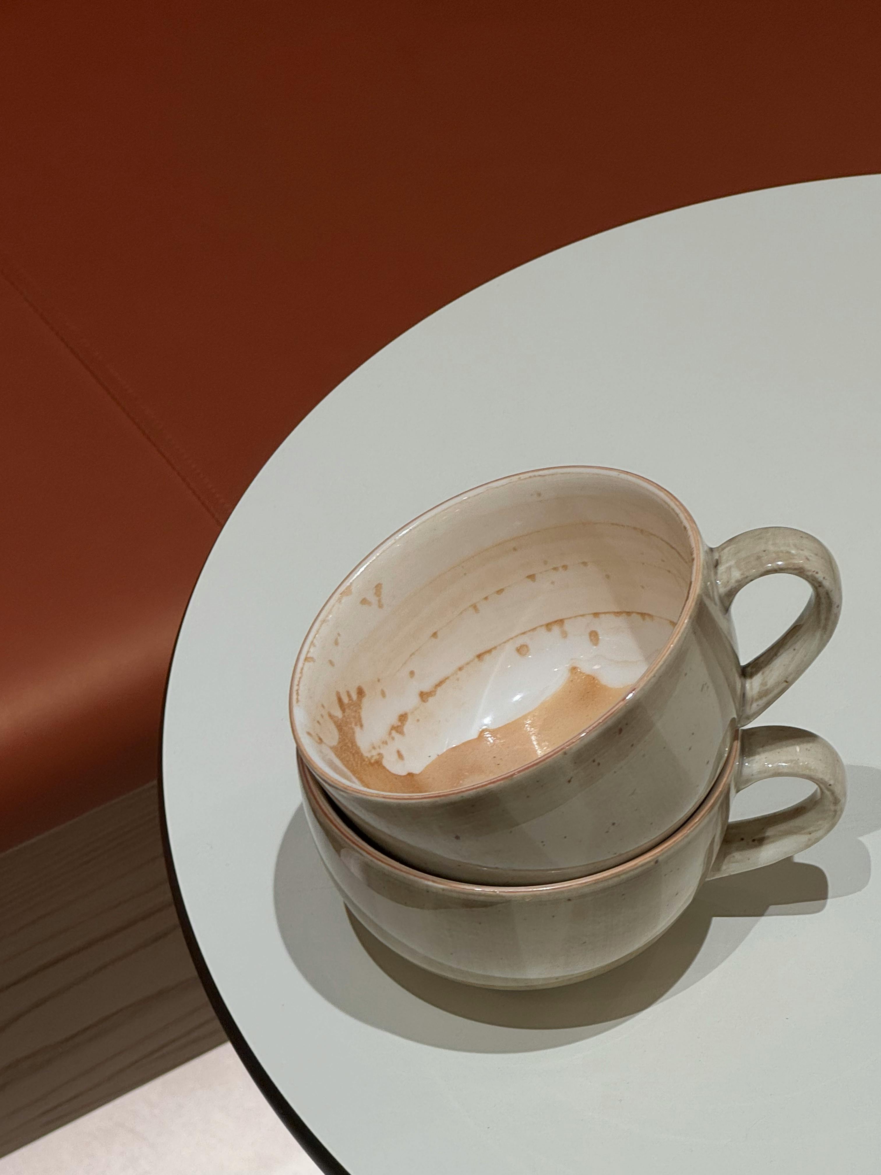 Kostnadsfria Två tomma keramiska kaffekoppar staplade på ett modernt vitt bord i en mysig miljö. Stock foto