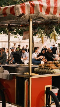 A vibrant street corn vendor cart with people enjoying food at an outdoor market.