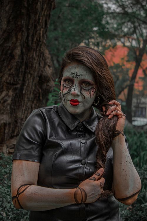 Free A woman with zombie makeup poses in a park in Mexico City, creating a spooky atmosphere. Stock Photo
