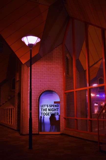 Moody urban scene with illuminated architecture, red accents, and inviting quote.