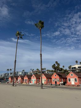 Charming red beach huts and palm trees on a sunny day in Oceanside, CA.