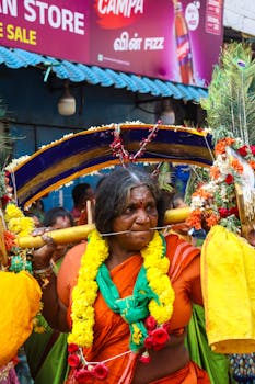 Devotee participating in a vibrant traditional procession with decorative elements.