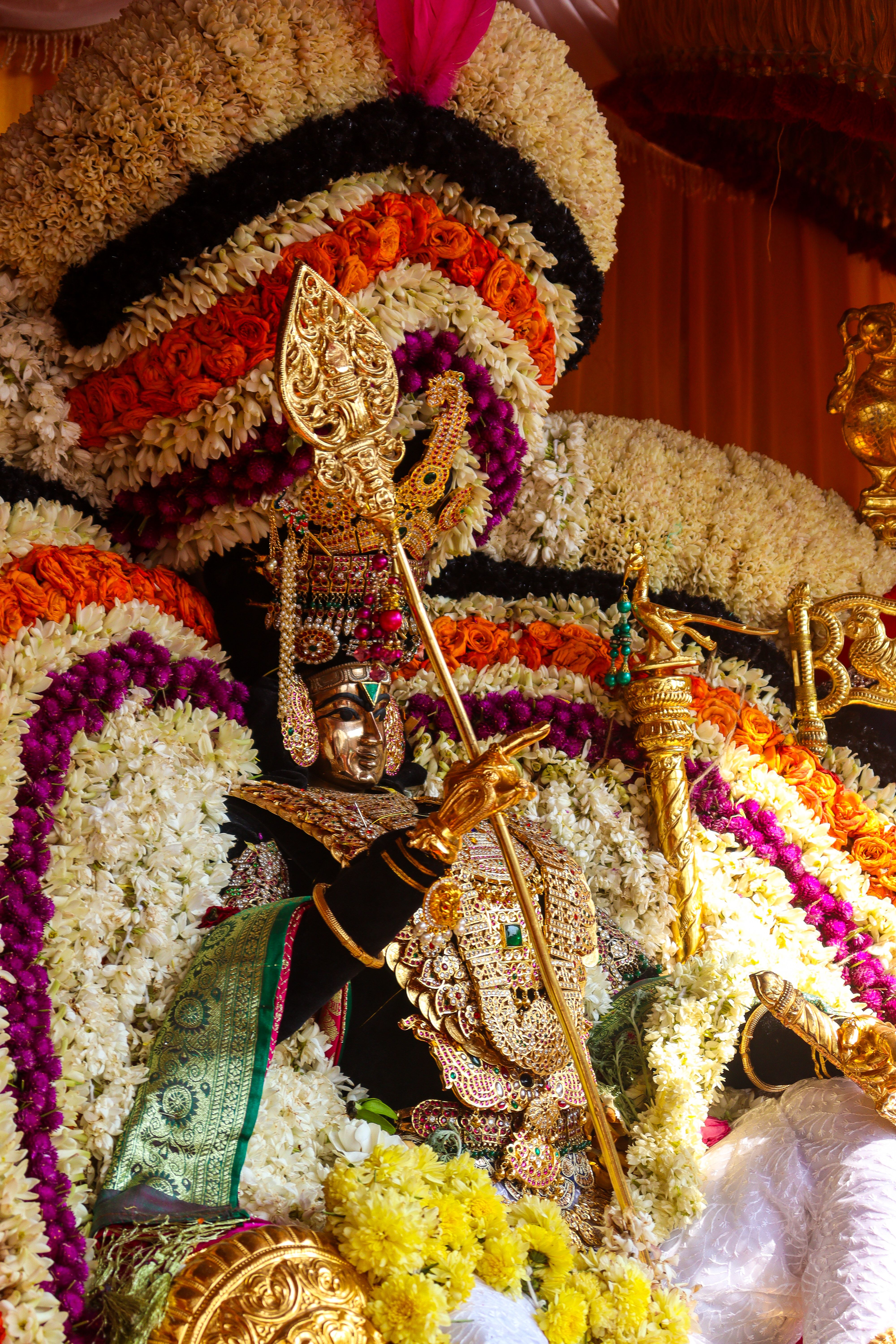 Close-up of a richly adorned deity statue with vibrant floral decorations.