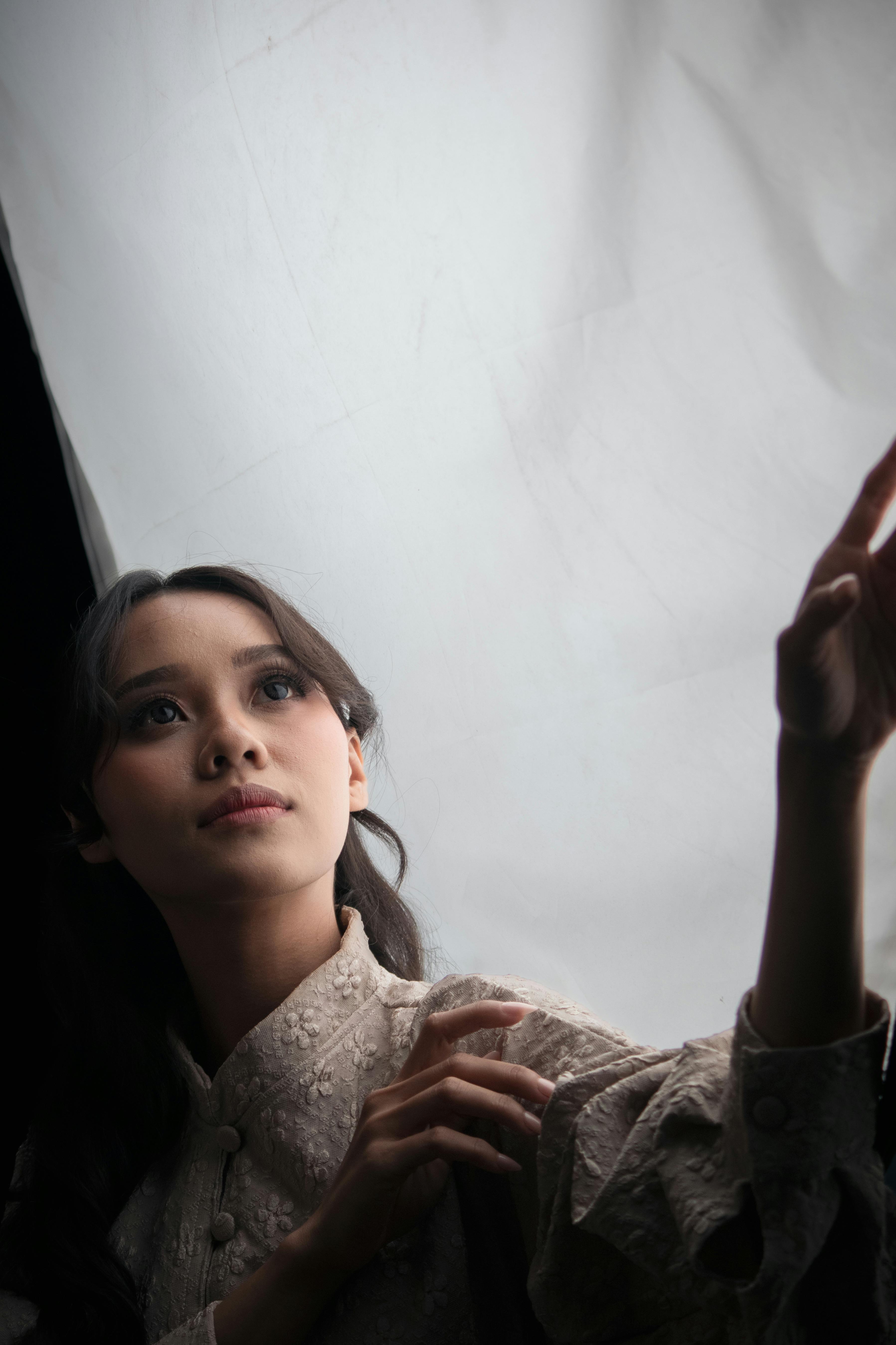 Gratis Una giovane donna in abiti tradizionali allunga la mano verso una luce intensa all'interno. Foto a disposizione