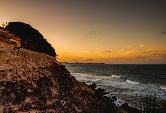 Dramatic sunset over the ocean with rugged cliffs in RN, Brazil.