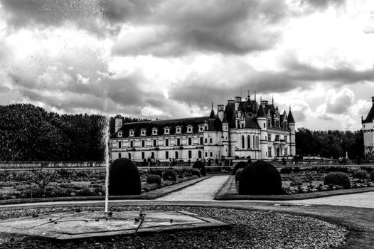 Historic Château de Chenonceau in black and white with a garden view.