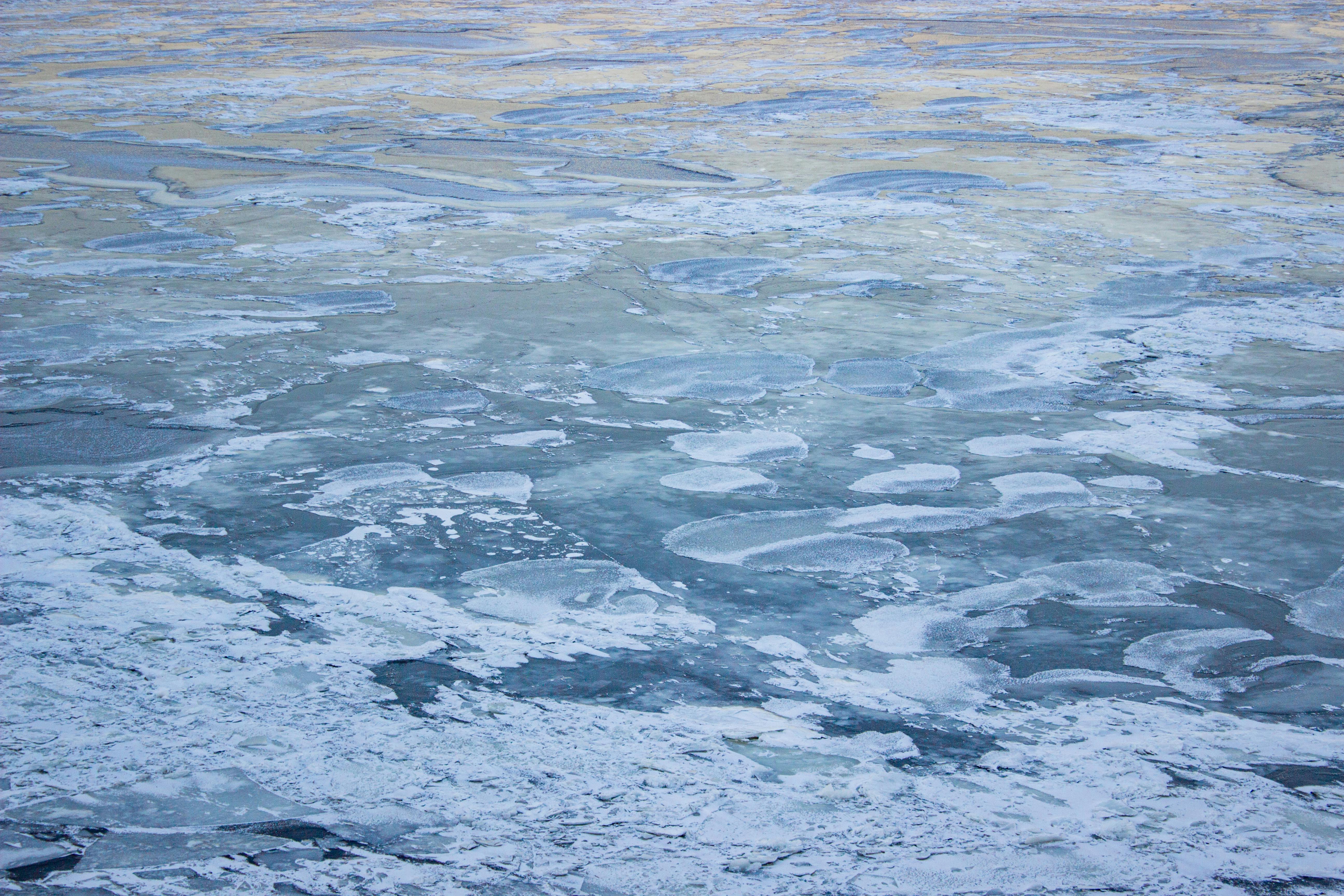 A serene view of a frozen water surface with intricate ice patterns at twilight.