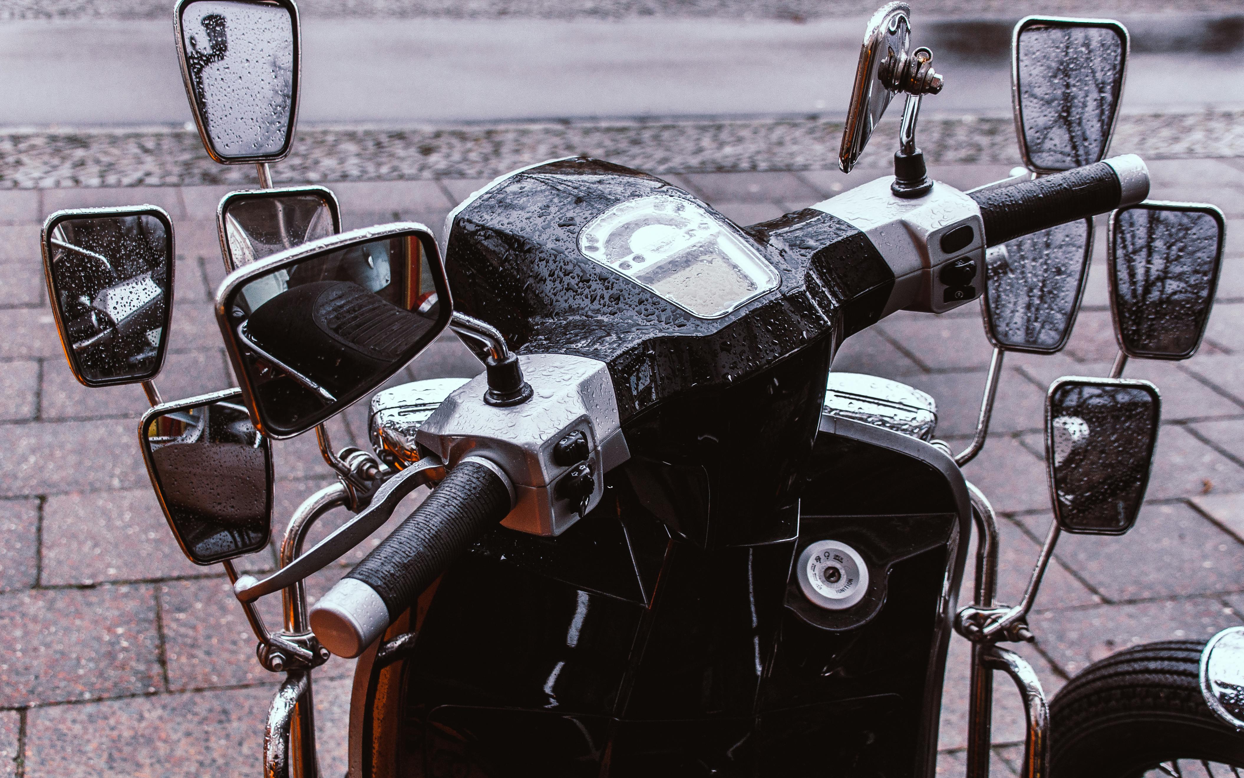 Gratis Primo piano del manubrio di uno scooter d'epoca decorato con numerosi specchietti e gocce di pioggia. Foto a disposizione
