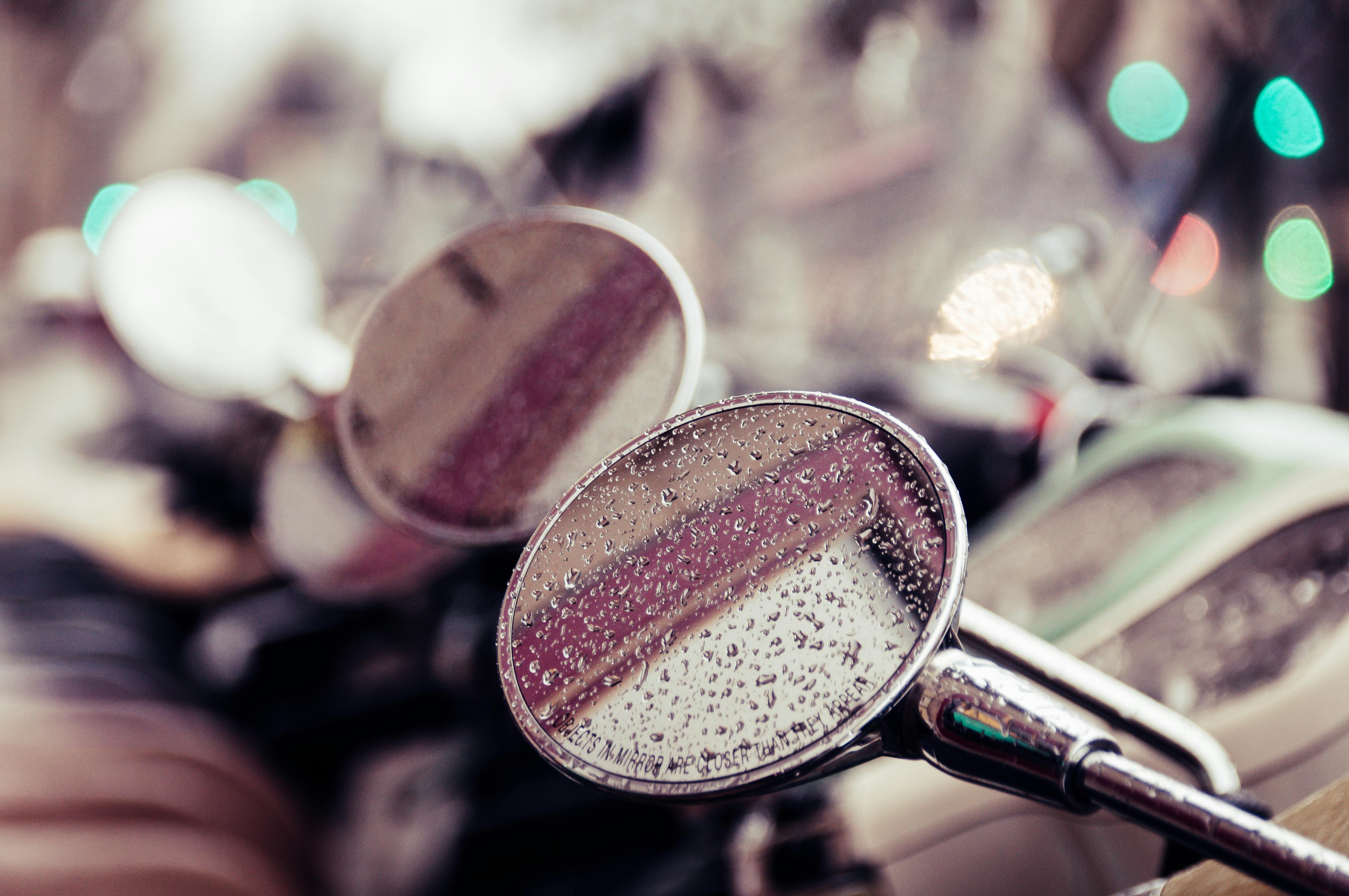 免费 特写镜头展现了被雨滴覆盖的摩托车后视镜，捕捉到一幅倒映的景象。 素材图片