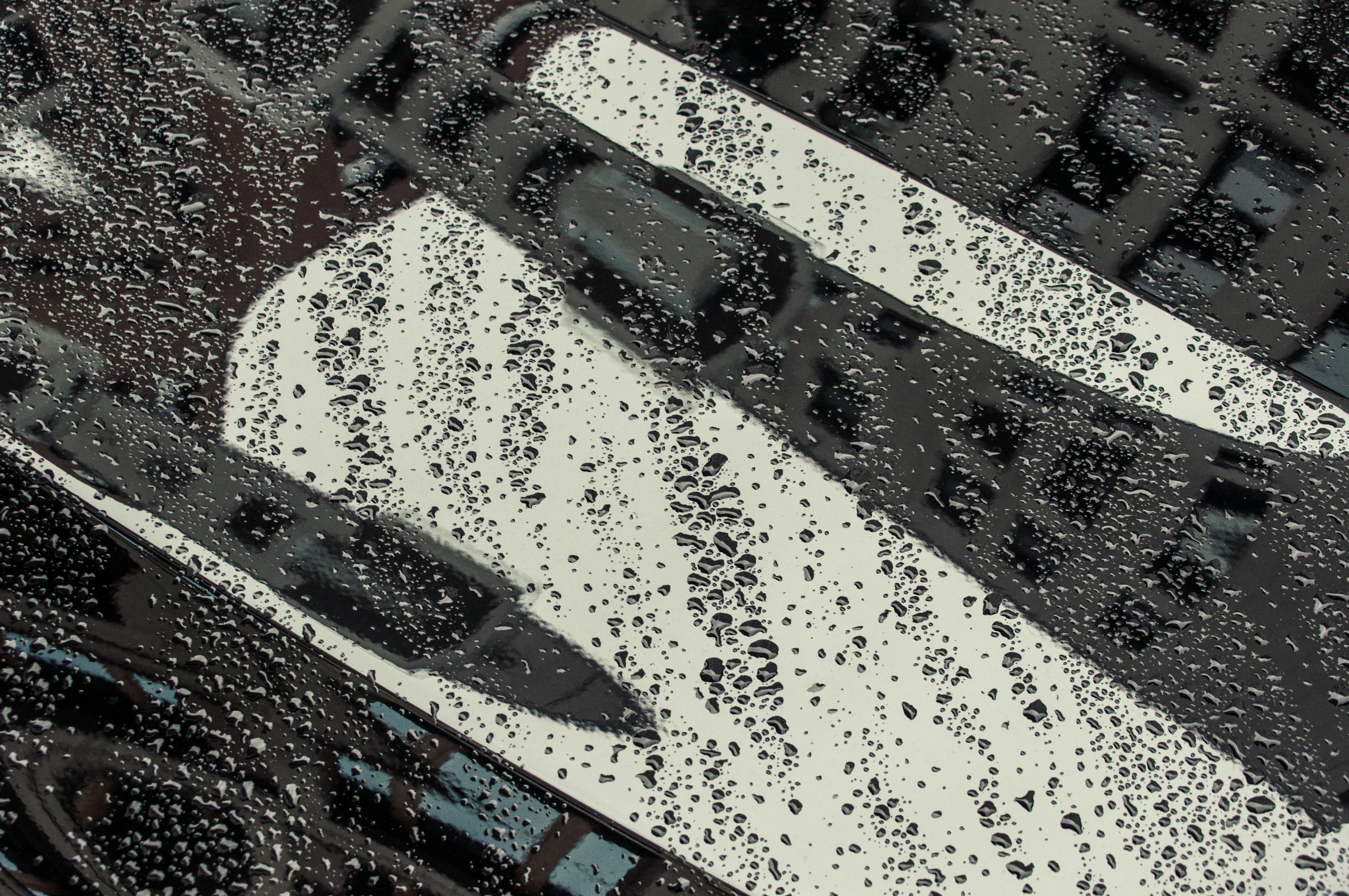 Free Close-up of raindrops on a car window reflecting a cityscape. Artistic and detailed. Stock Photo