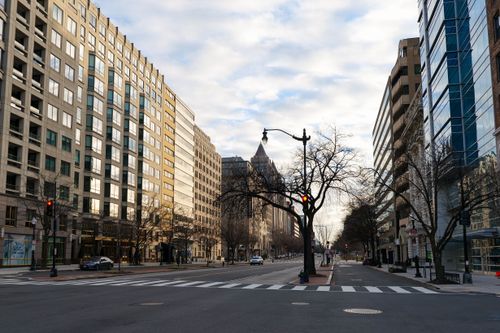 Free A deserted street in Washington DC showcasing modern urban architecture under a cloudy sky. Stock Photo