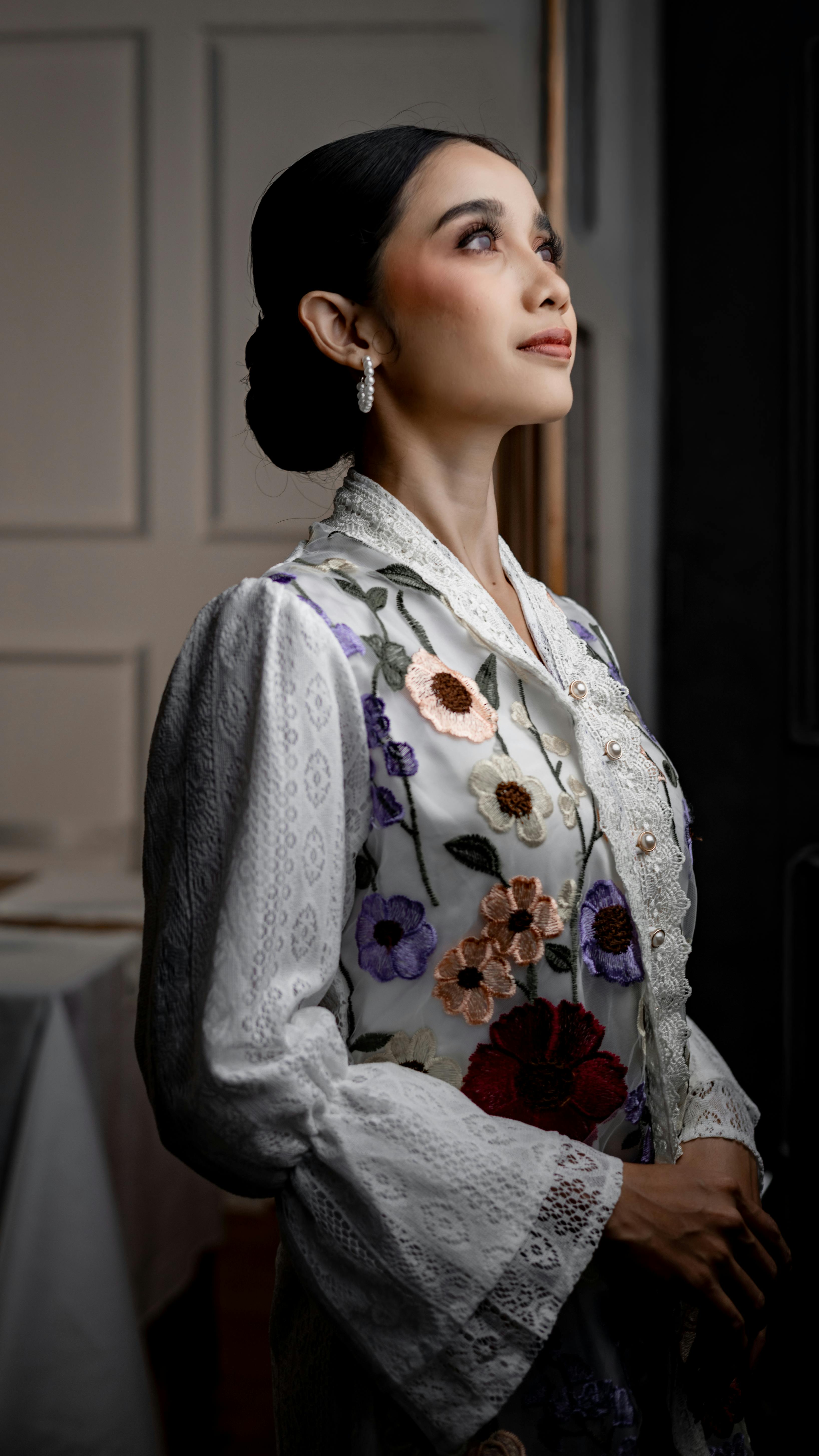 無料 インドネシア、ジャカルタの屋内で花柄の伝統的な衣装を着た女性の優雅な肖像画。 写真素材