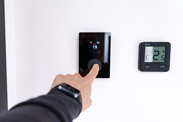 Hand adjusting a digital smart thermostat