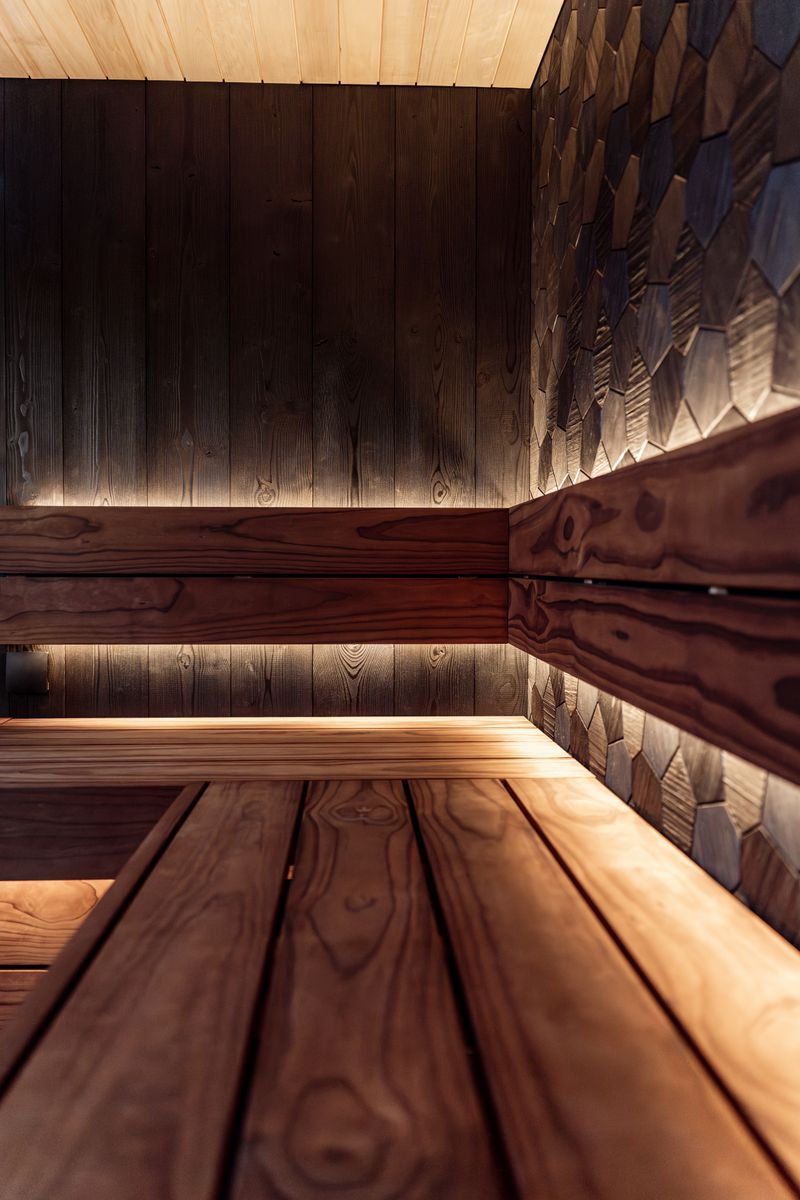 Modern infrared-style sauna interior with dark wood paneling and warm accent lighting