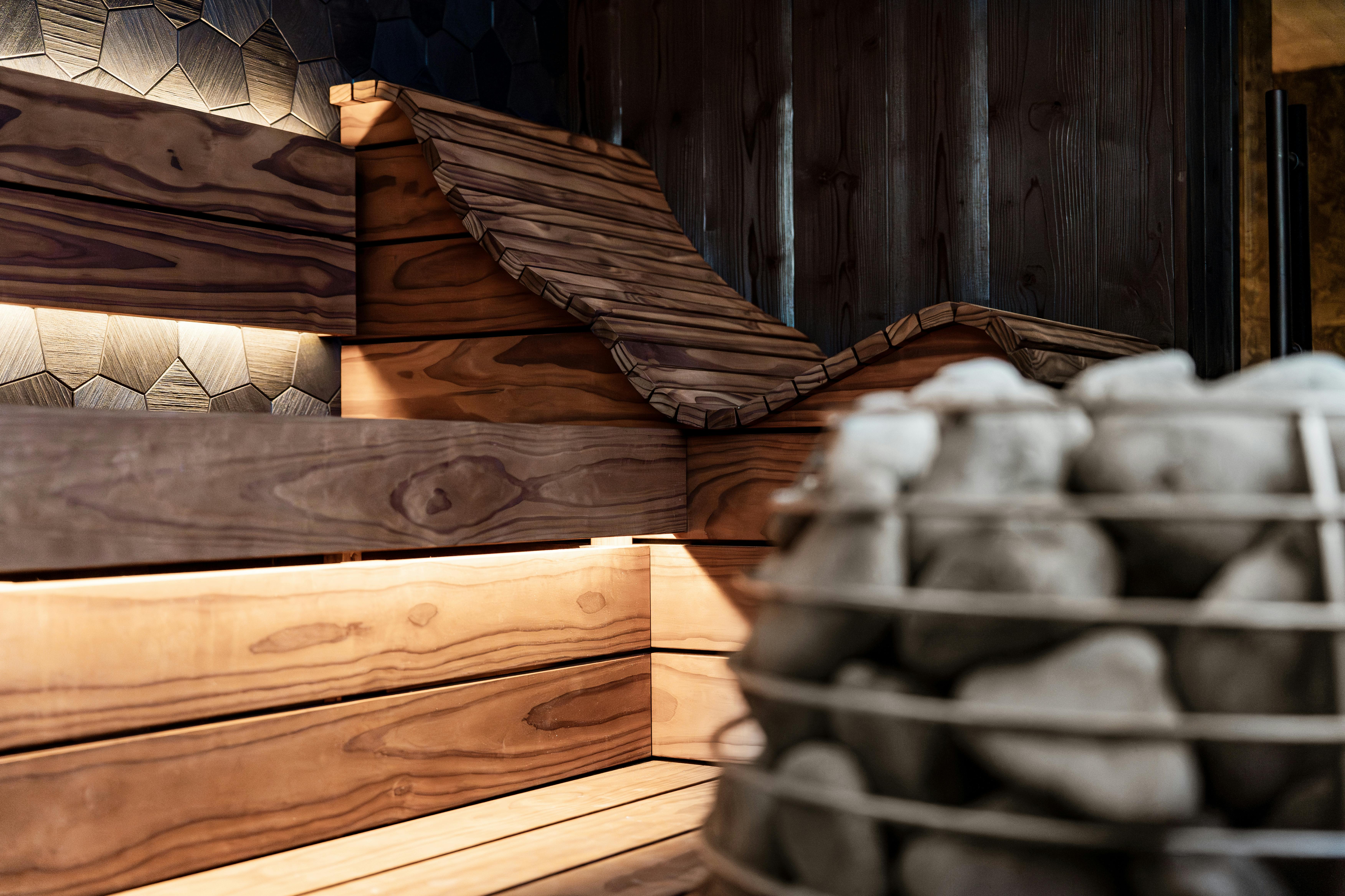 Découvrez le design d'un sauna élégant doté de panneaux en bois et d'un poêle en pierre.