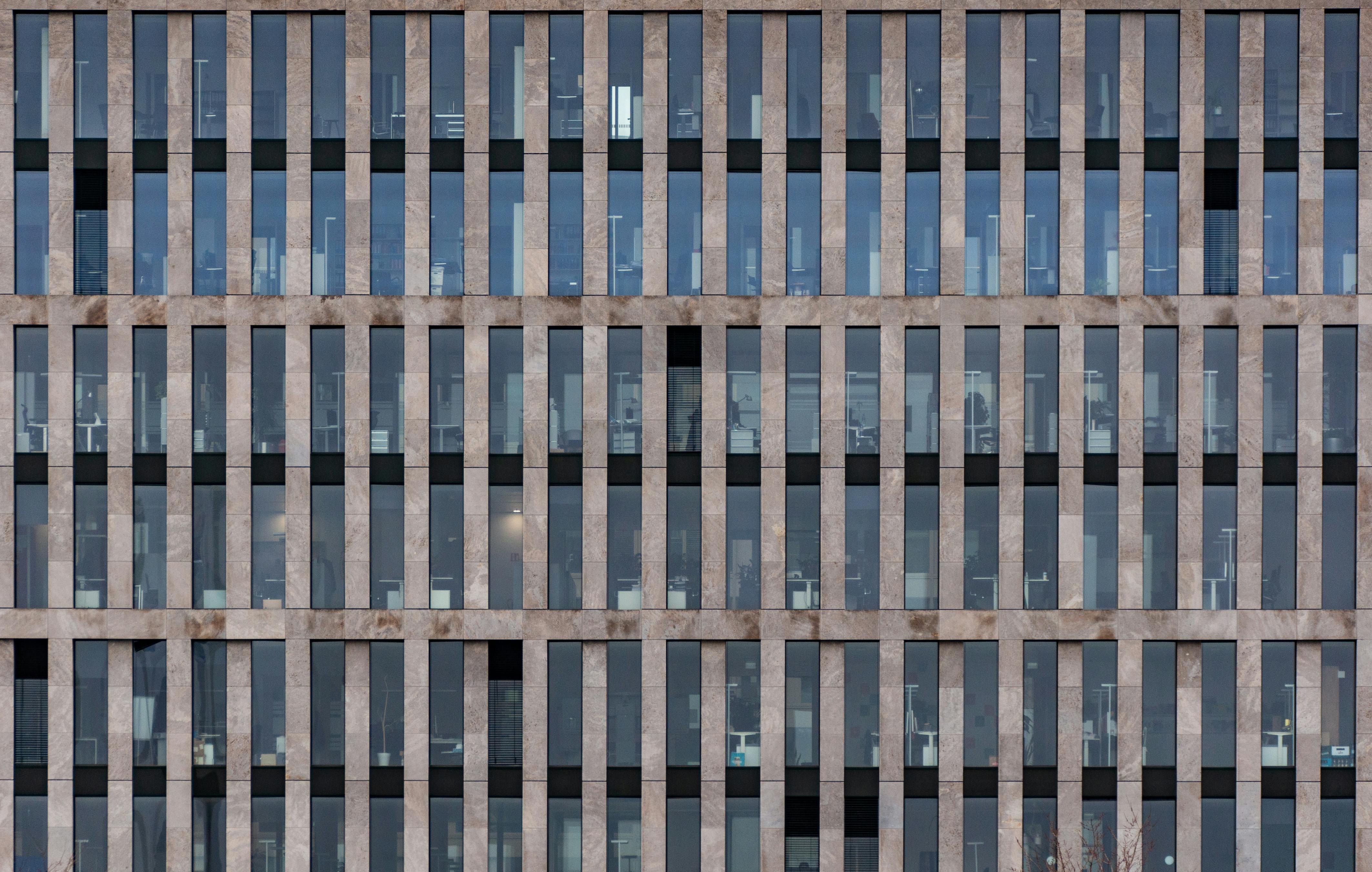 Free Front view of a modern office building's symmetrical facade with vertical lines. Stock Photo