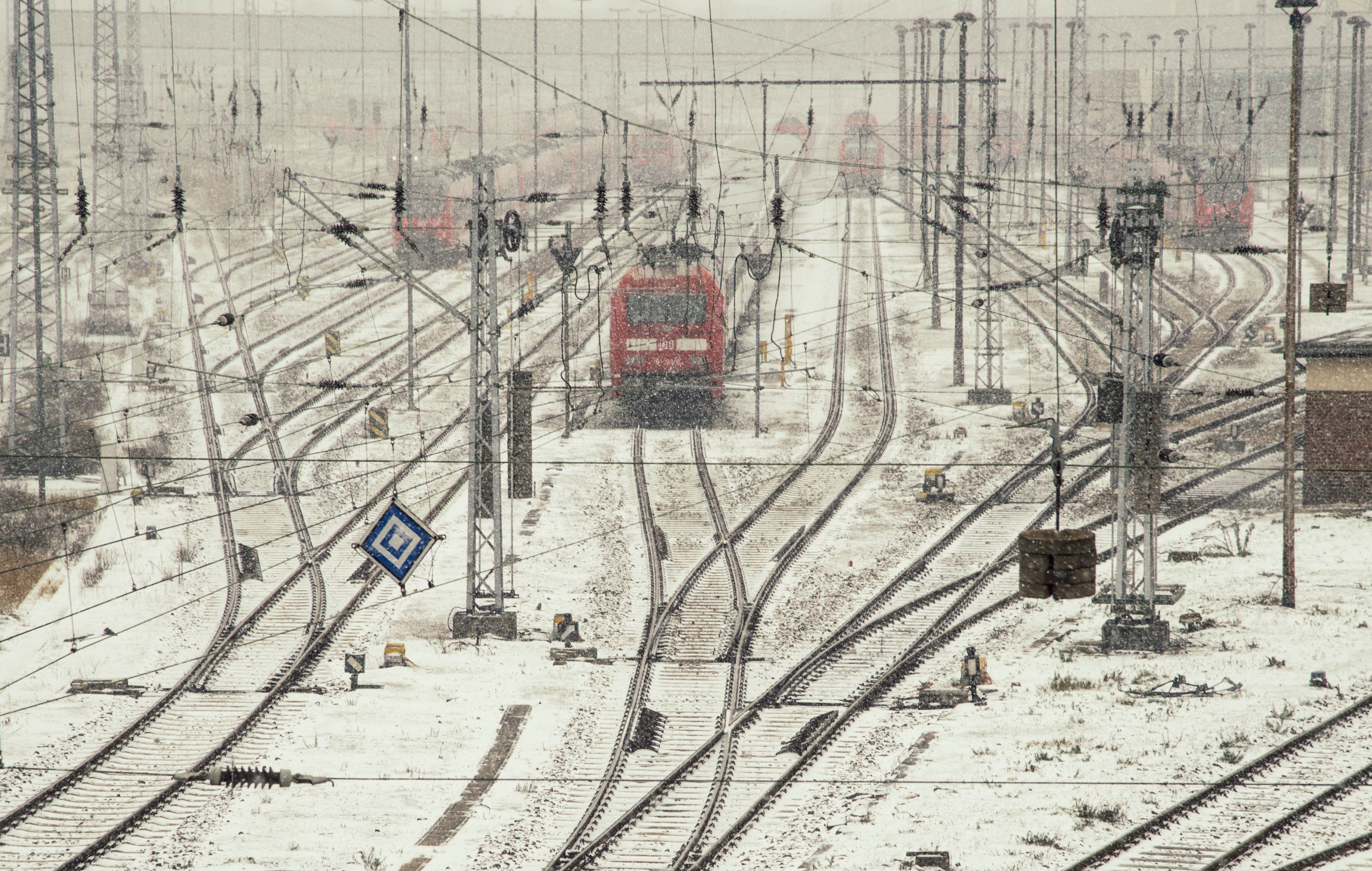 Bezpłatne Czerwony pociąg na pokrytych śniegiem torach kolejowych w śnieżny zimowy dzień. Zdjęcie z galerii