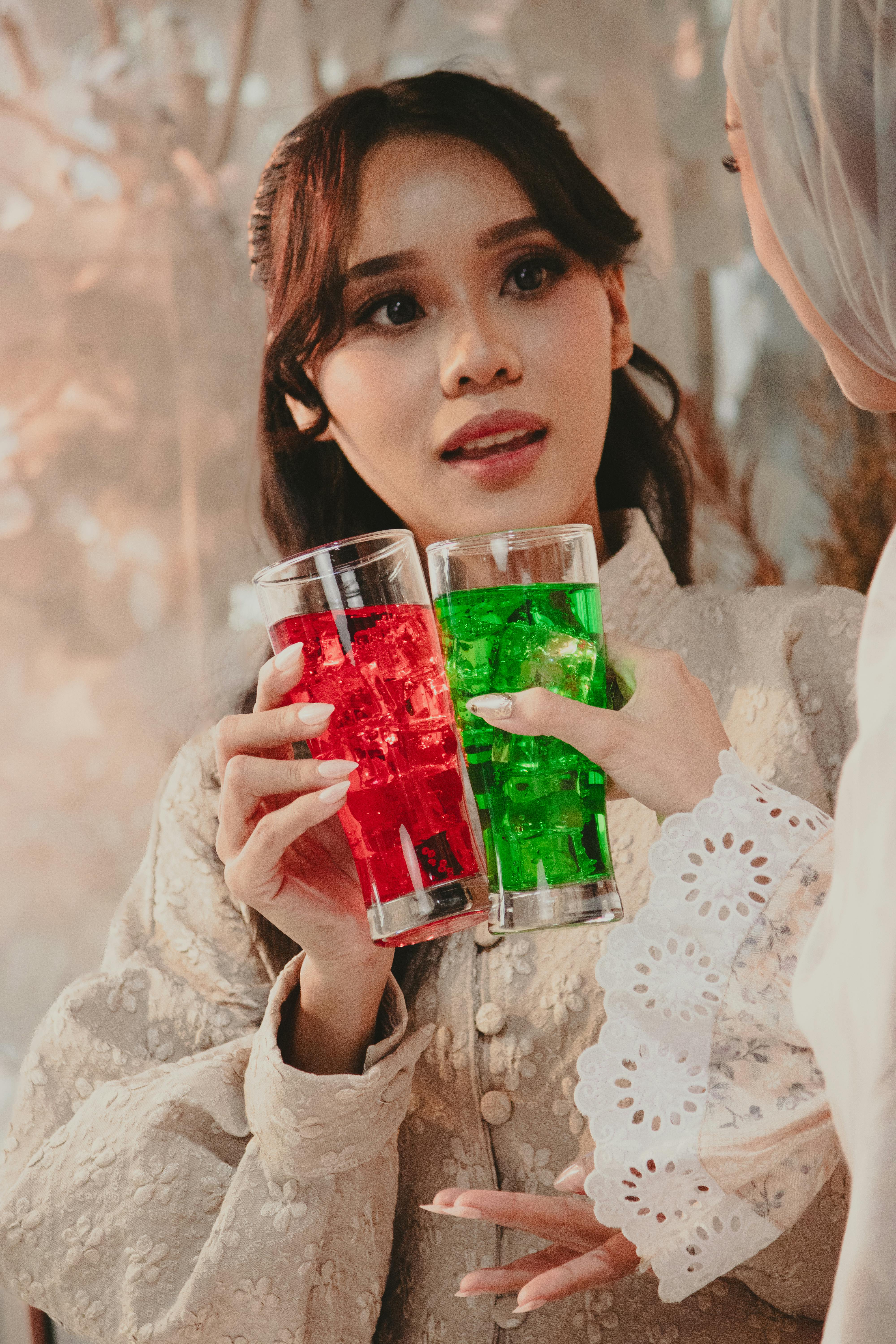 Gratis Due donne brindano con vivaci drink rossi e verdi in un elegante ambiente interno. Foto a disposizione