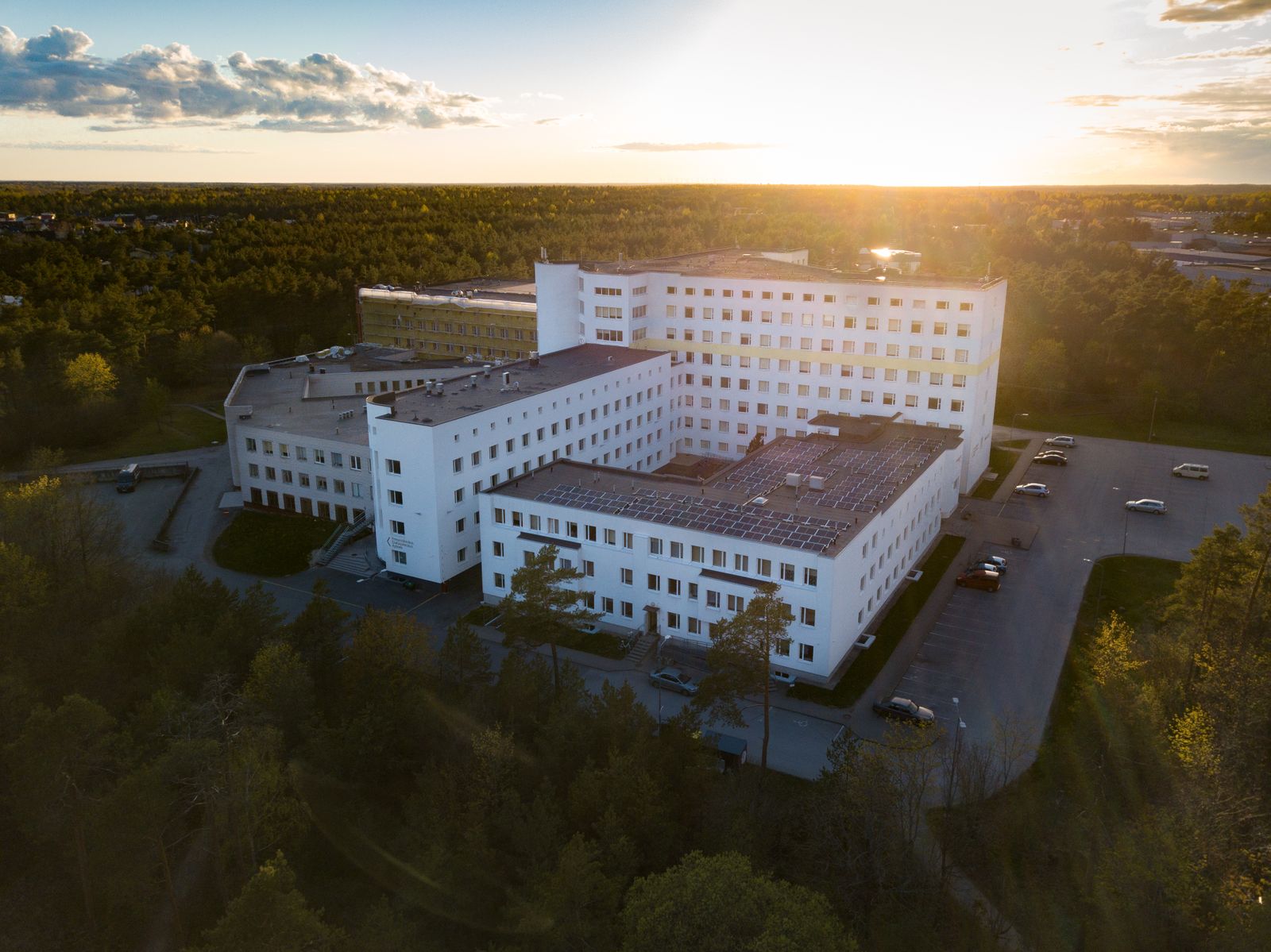 Aerial view of a modern hospital building surrounded by greenery at sunset