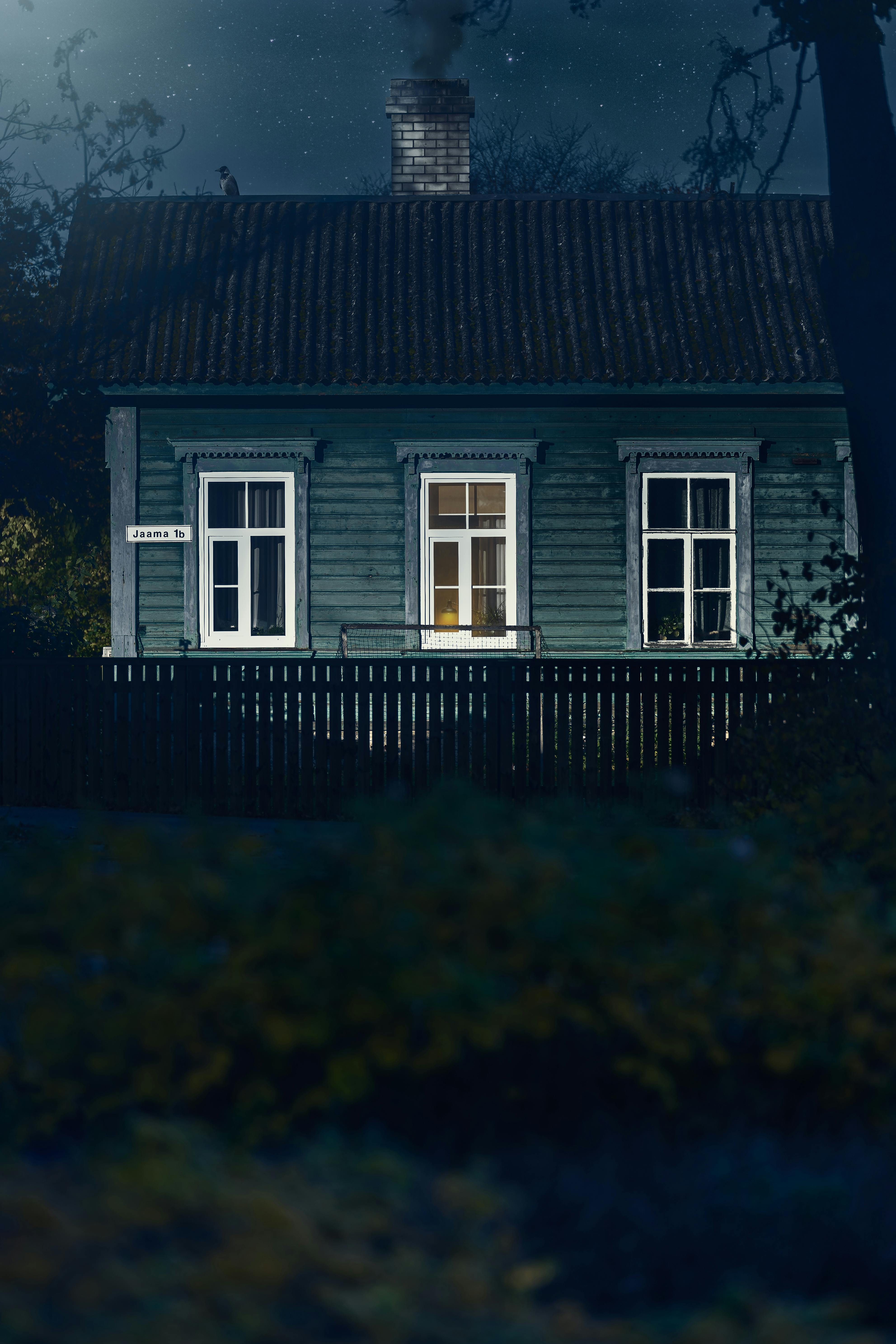 Kostenlos Ein warmes Licht strahlt aus einem malerischen Holzhaus unter dem sternenklaren Nachthimmel. Stock-Foto