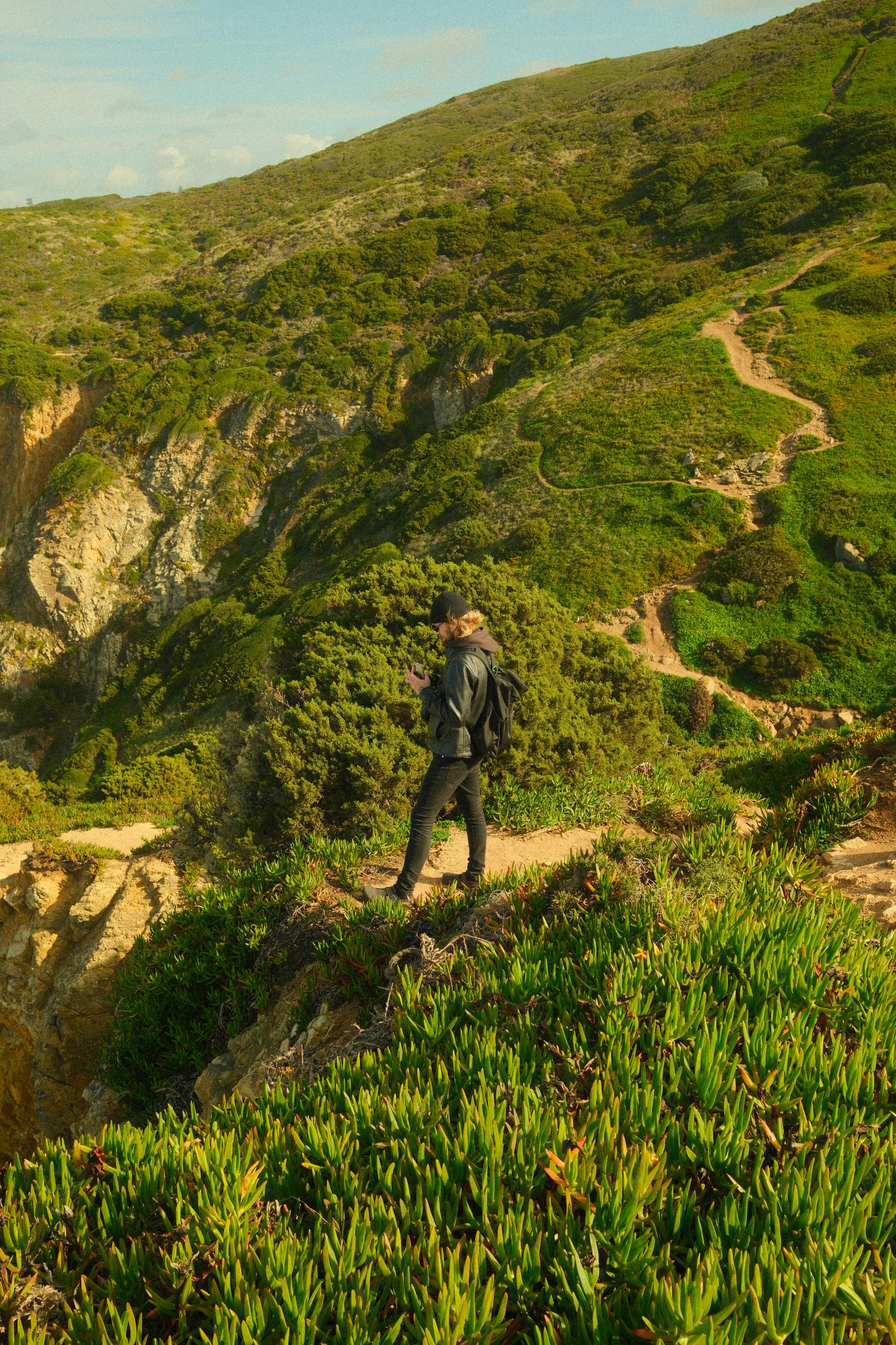 無料 ポルトガルのコラレスにある緑豊かな丘の中腹に、素晴らしい景色に囲まれたハイカーが立っています。 写真素材