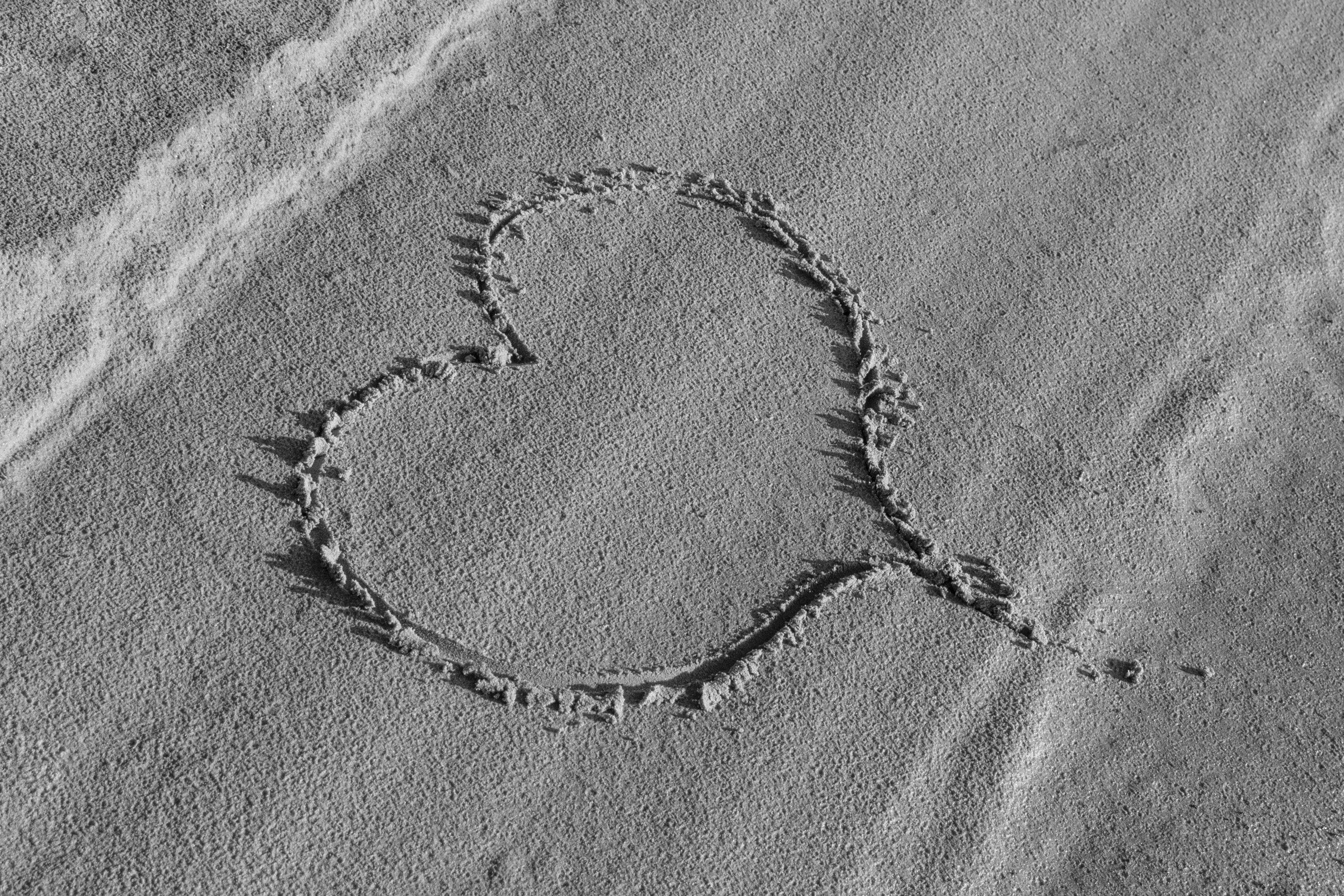 Gratis Hjerteform tegnet på sand, som fanger romantiske strandstemninger, i svart-hvitt. Arkivbilde